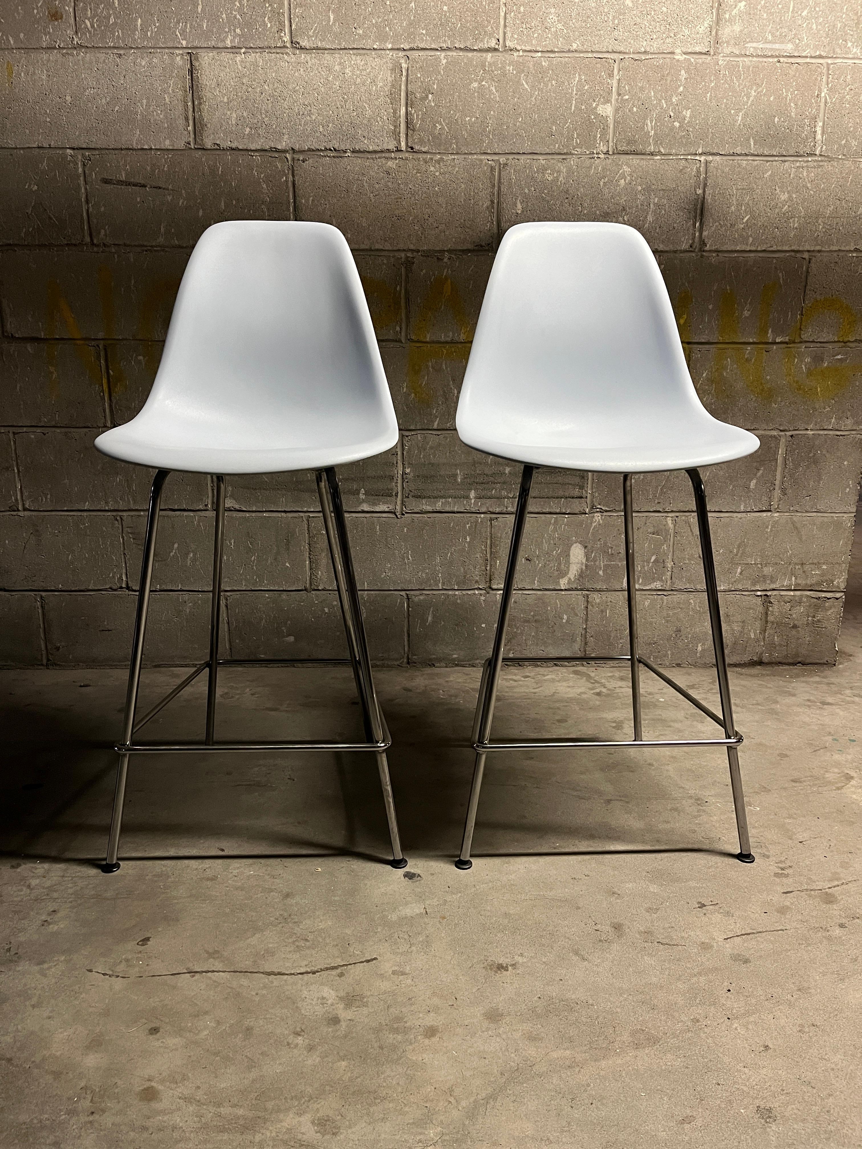 One iconic pair of light gray molded plastic bar stools by Charles & Ray Eames for Herman Miller, 2010s. These beautiful stools were very lightly used. The perfect combination of comfort and style featuring gray molded seats with chromes steel legs.
