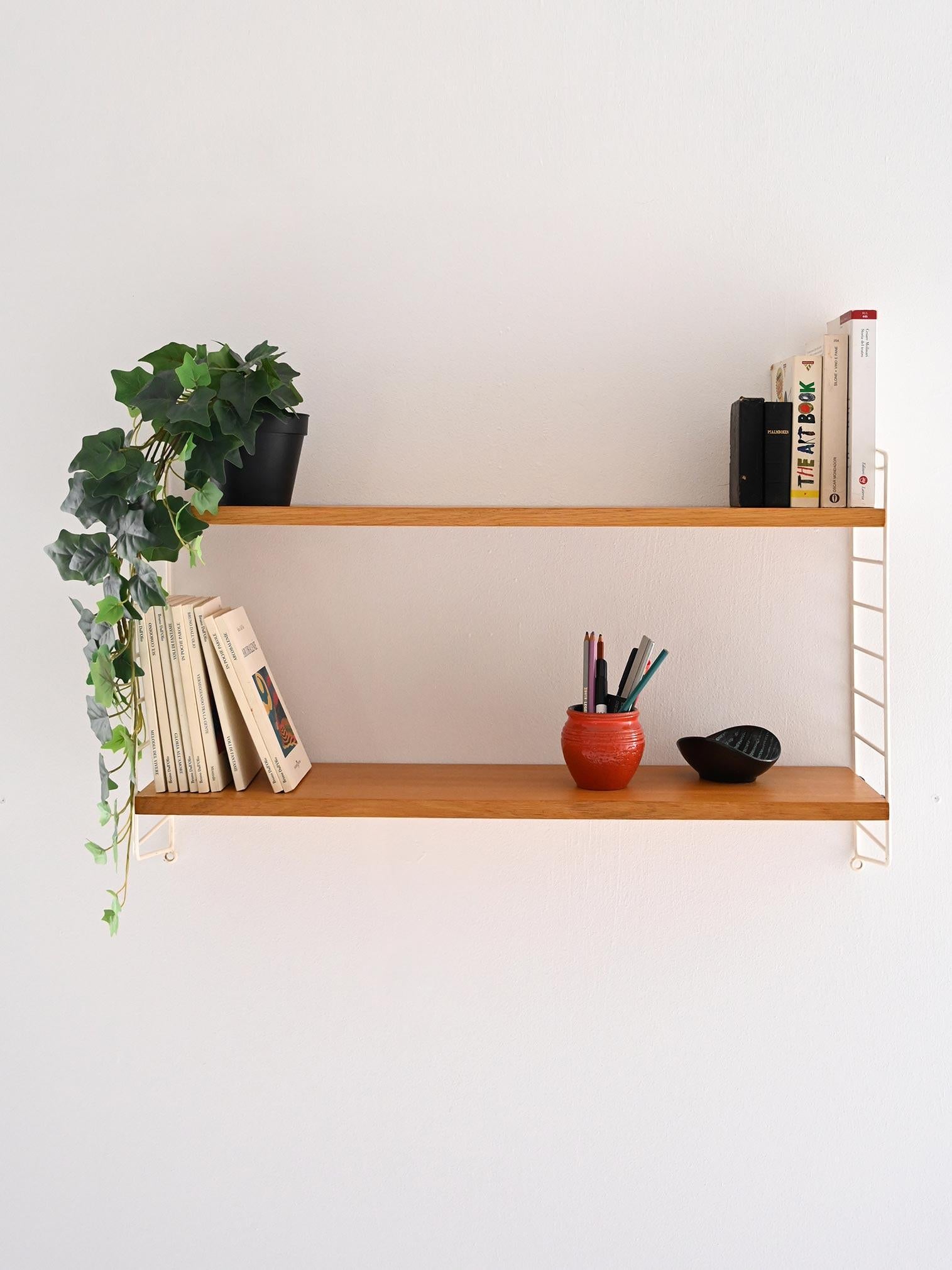 Sistema scandinavo di scaffalature a muro composto da 2 mensole in legno di rovere e struttura laterale in metallo rivestito di colore bianco. 

Perfetto per esporre libri e oggetti decorativi. In buone condizioni. Può presentare segni di usura