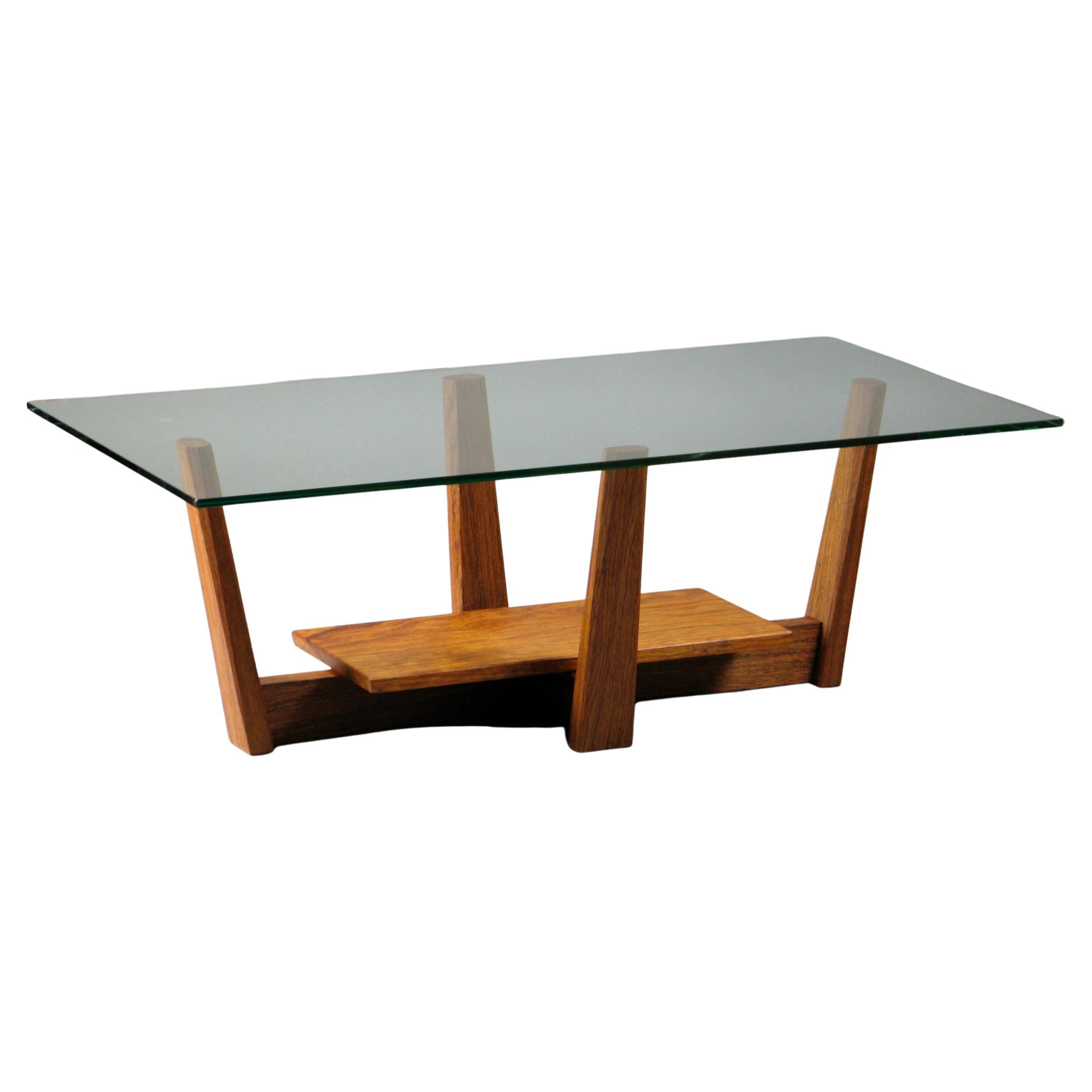 The Novo Coffee Table embodies refined simplicity and exceptional craftsmanship. Its figured bubinga base, carefully shaped with tapered legs and chamfered edges, creates a striking visual flow that guides the eye from the solid base up to the