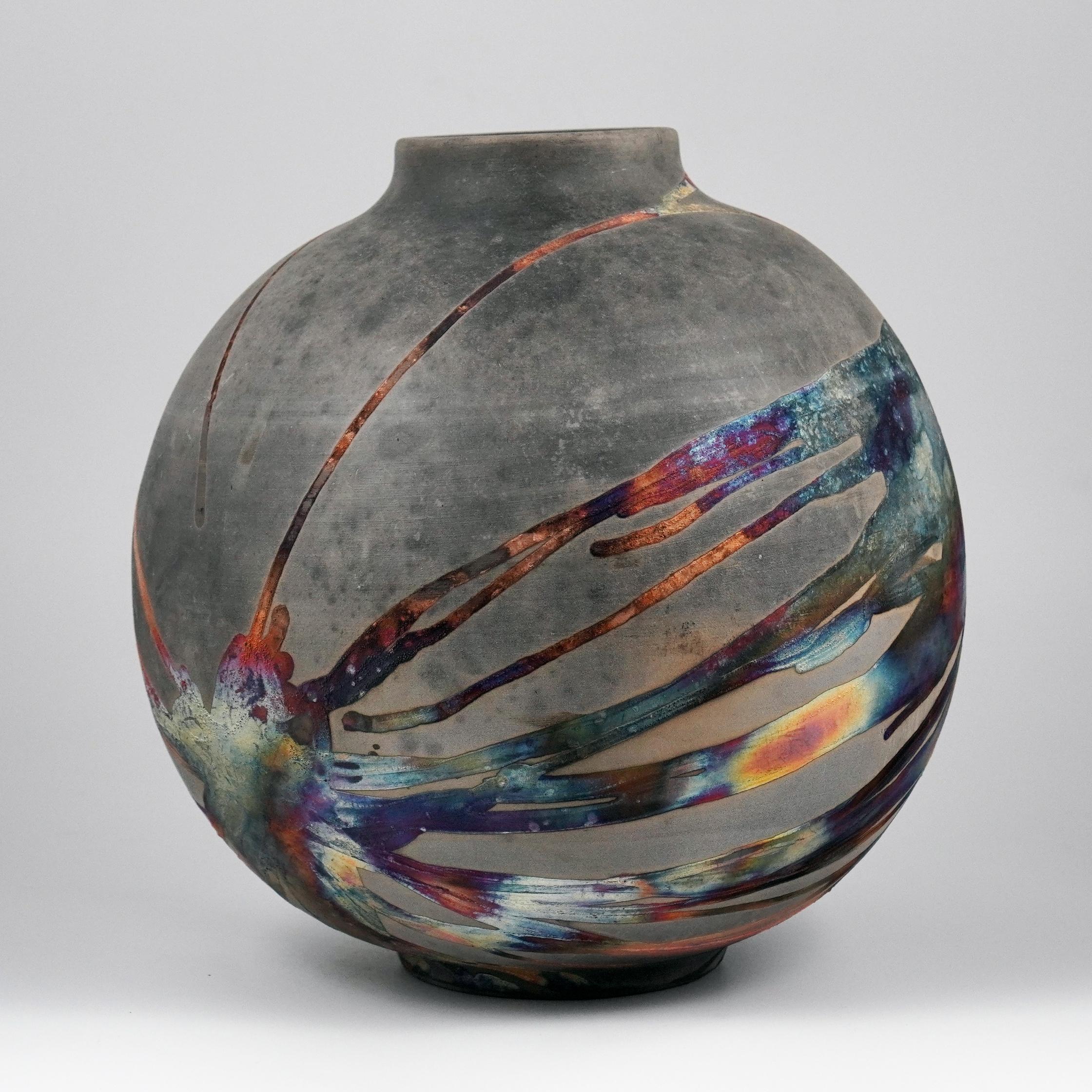 A mesmerizing sight to behold as soon as the rainbow-like patinas catch your eye. This Globe Vase is a round, capacious piece produced using the Raku technique, resulting in a beautiful unpredictable finish. This vase would be the perfect