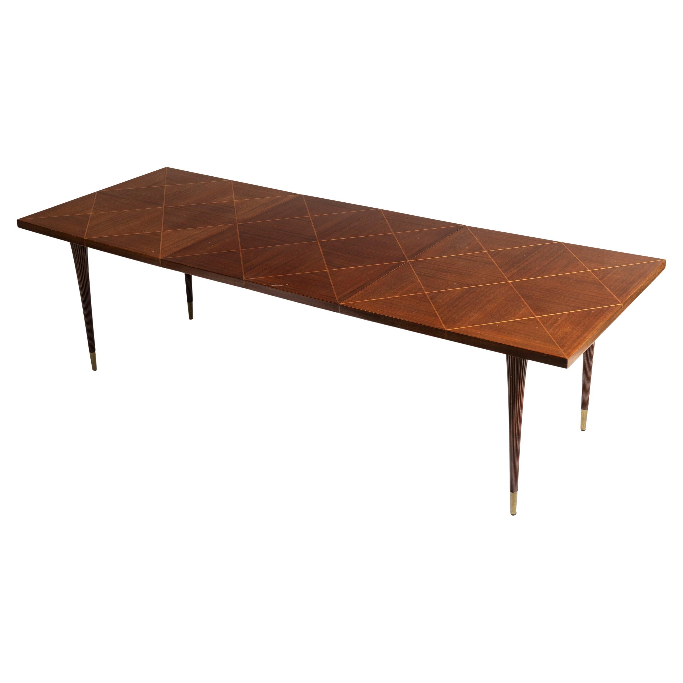 Timeless and distinctive, Tommi Parzinger furniture embodies modern design across many eras and styles. Crafted with mahogany, with geometric inlaid fruitwood and slender tapered legs ending with patinated brass sabots.  this dining table