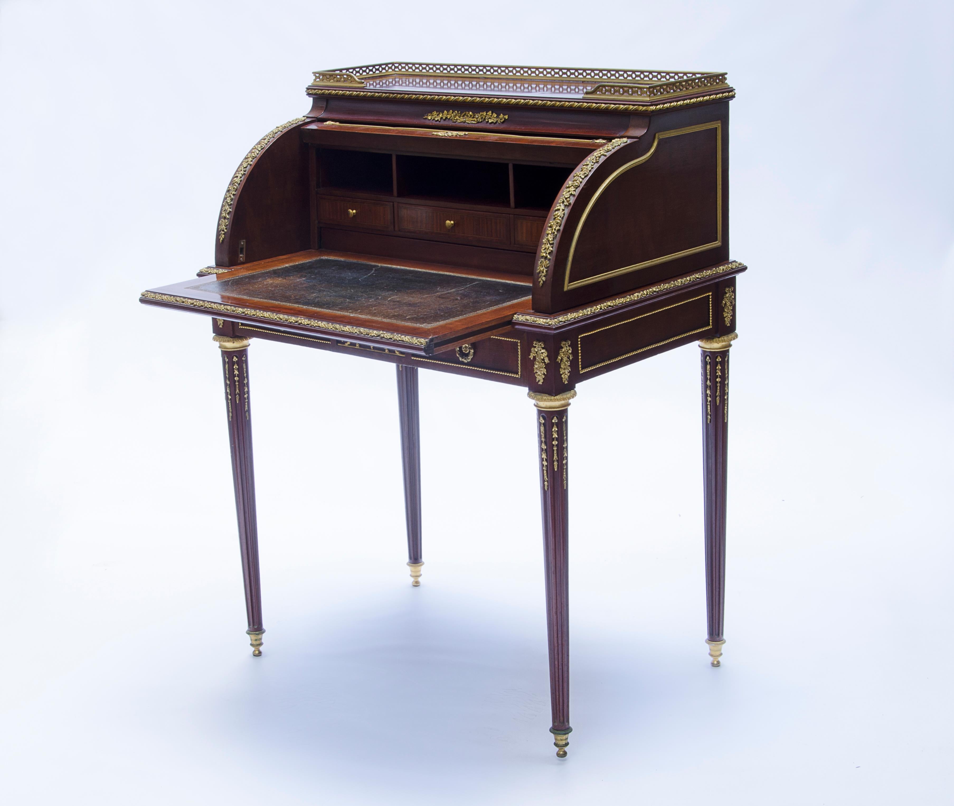 Bureau cylindrique avec stores, en bois plaqué avec un bord en bronze sur le dessus, détails en bronze avec des fleurs sur le cadre et des médaillons. La frise centrale et le tiroir présentent des satyres portant un Bacchus ivre entouré de