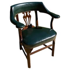 Poltrona in mogano rivestita in pelle verde cacciatore con rifiniture in ottone a chiodini