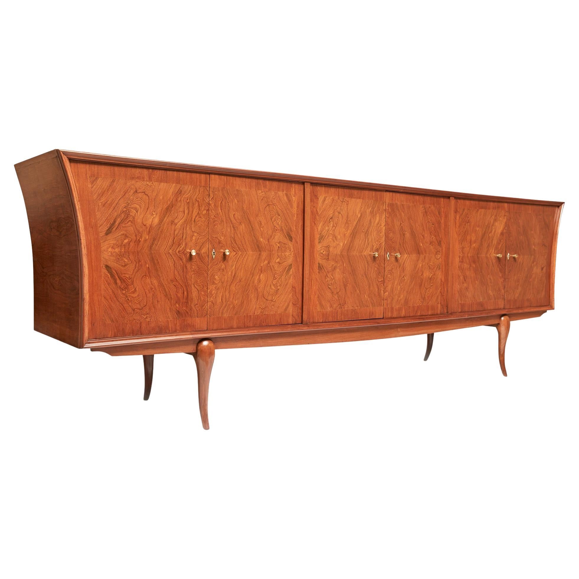 Available today, this magnificent Mid-Century Modern credenza is entirely made of Caviuna hardwood and consists of six doors, three storage cabinets, six shelves and four drawers. The sides are curved and the structure rests on four legs. The wood