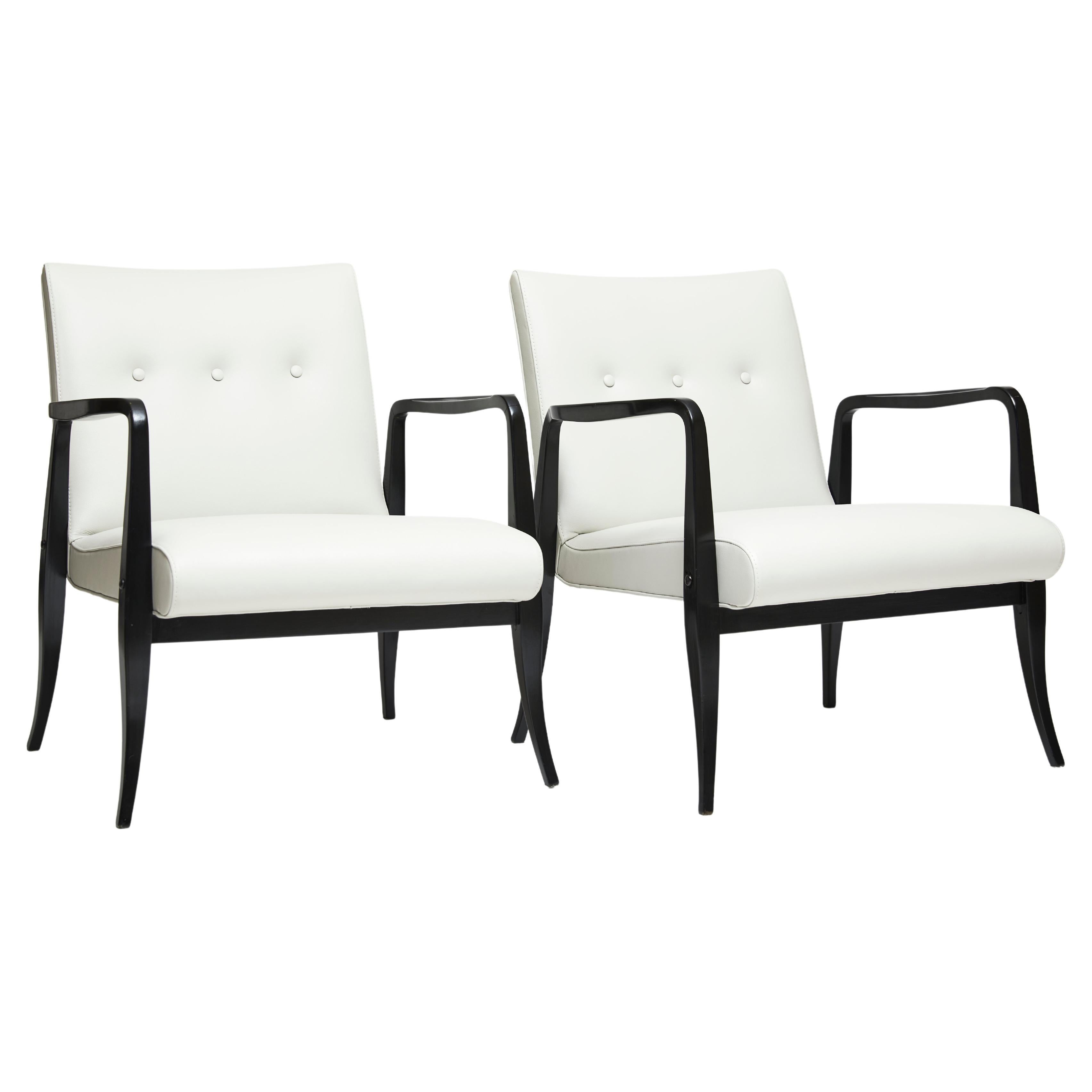 Available now, this beautiful pair of Brazilian Modern armchairs are made of ebonized Pau Marfim hardwood & white leather in buttone style. 

The structure is composed of curved arms & feet, and were designed by Joaquim Tenreiro in the 1940’s. The