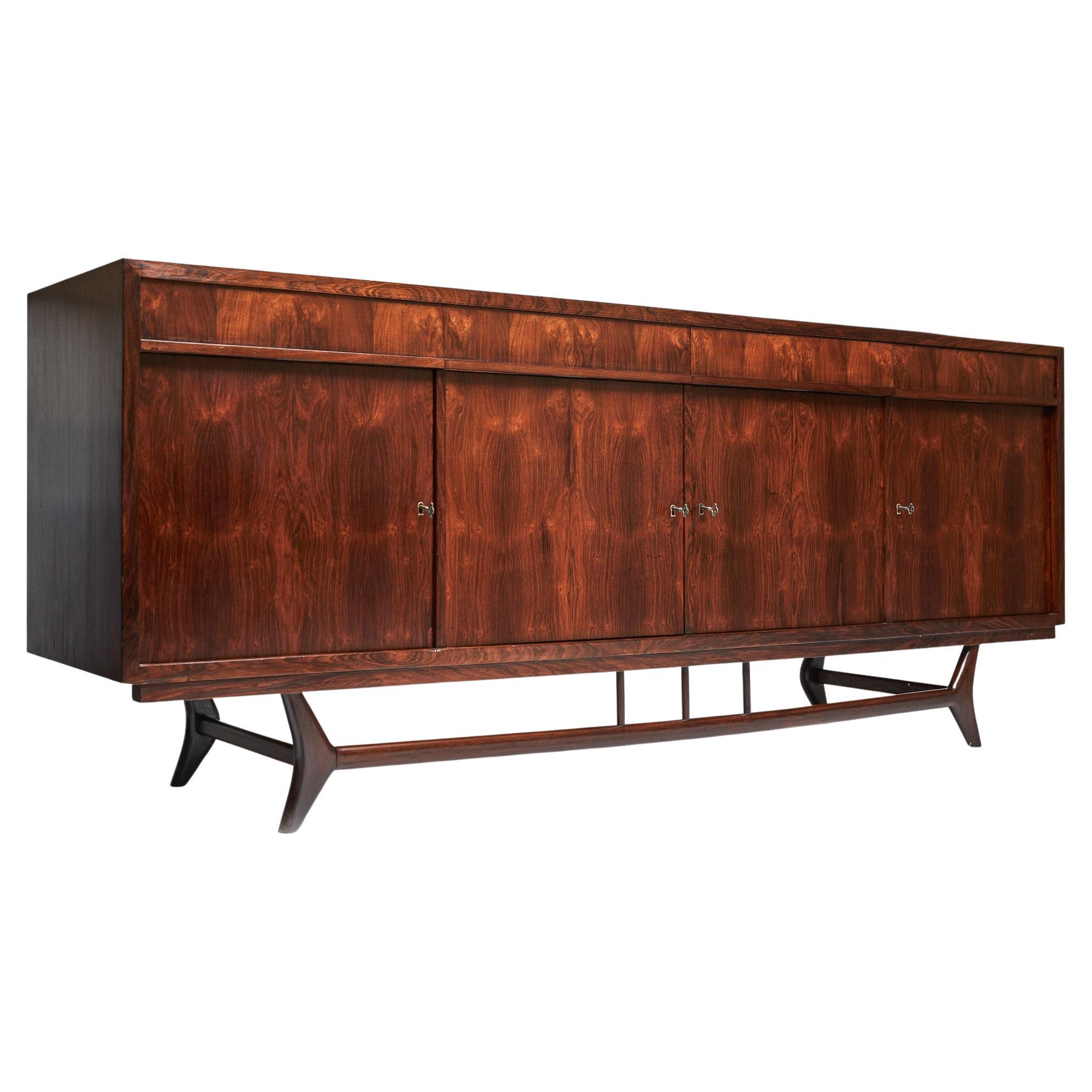 Available today, this Brazilian Modern Credenza in Hardwood and Brass finishes designed by Moveis Aparecida in sixties is exquisite!

This spectacular mid-century modern credenza is made of finest Brazilian rosewood, as known as Jacaranda and has 6