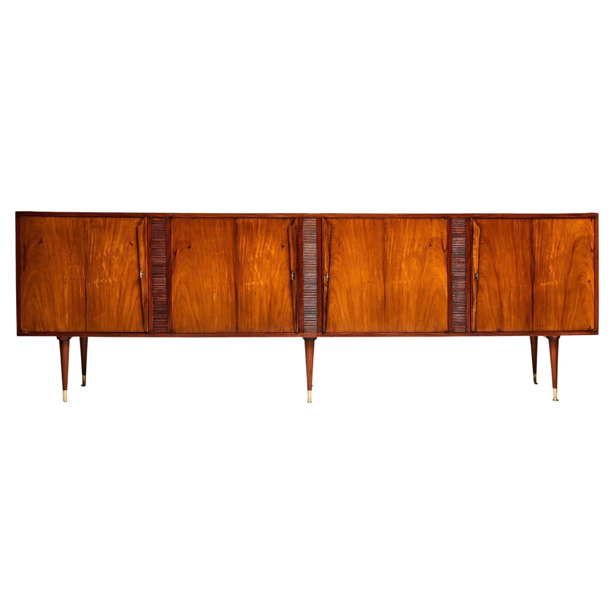 Available today, this Giuseppe Scapinelli’s stunning credenza is entirely made of Caviuna hardwood and features six bronze tipped tapered legs and has four doors, four hardwood drawers and 3 shelves. The original brass keys are available. The piece