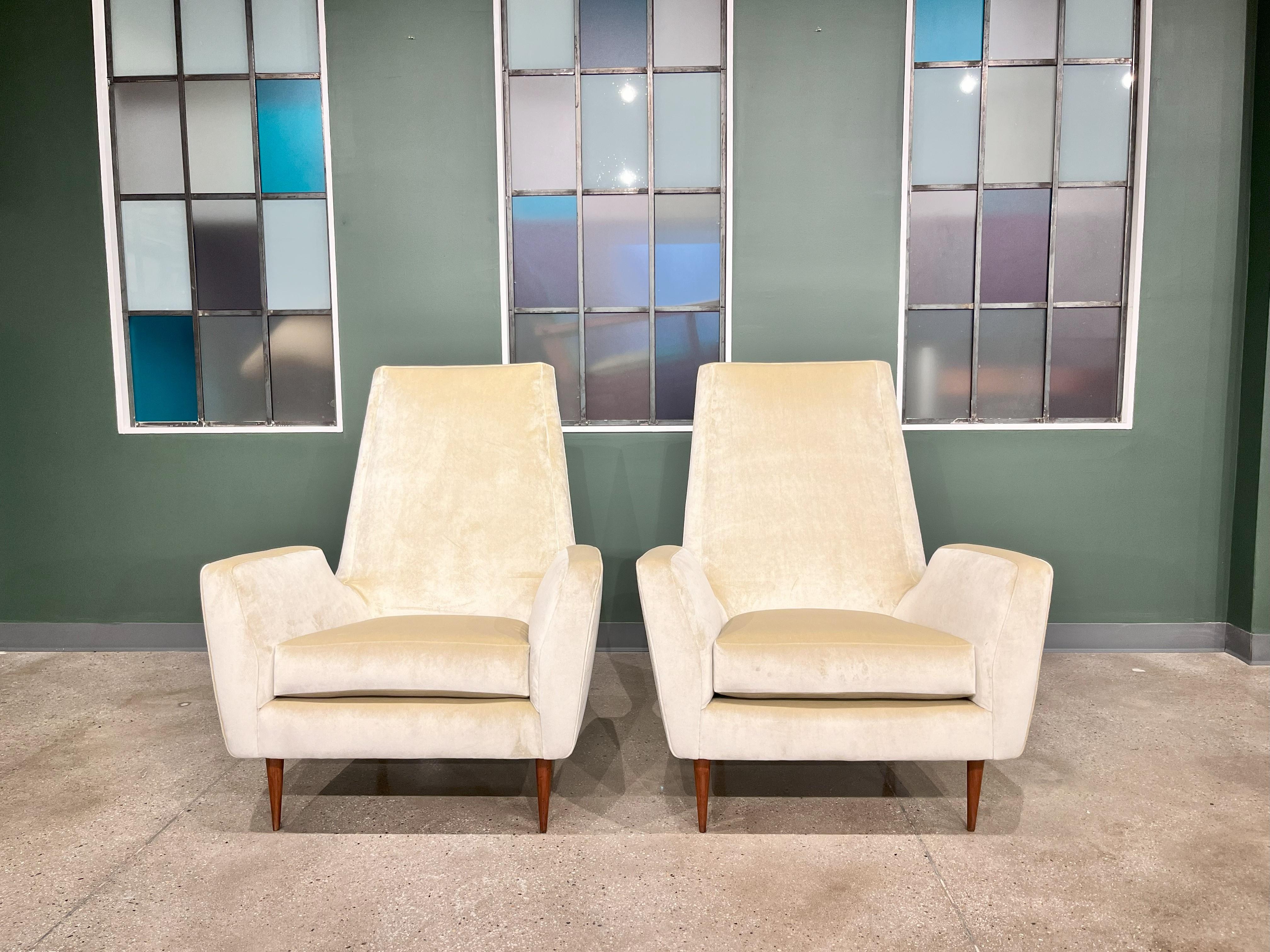 This pair of two high back armchairs has the typical Scapinelli style with its delicate lines and soft sensual shapes. The chairs rest on straight tapered legs supporting the sophisticated Beige Velvet cushions. The chairs are both comfortable with