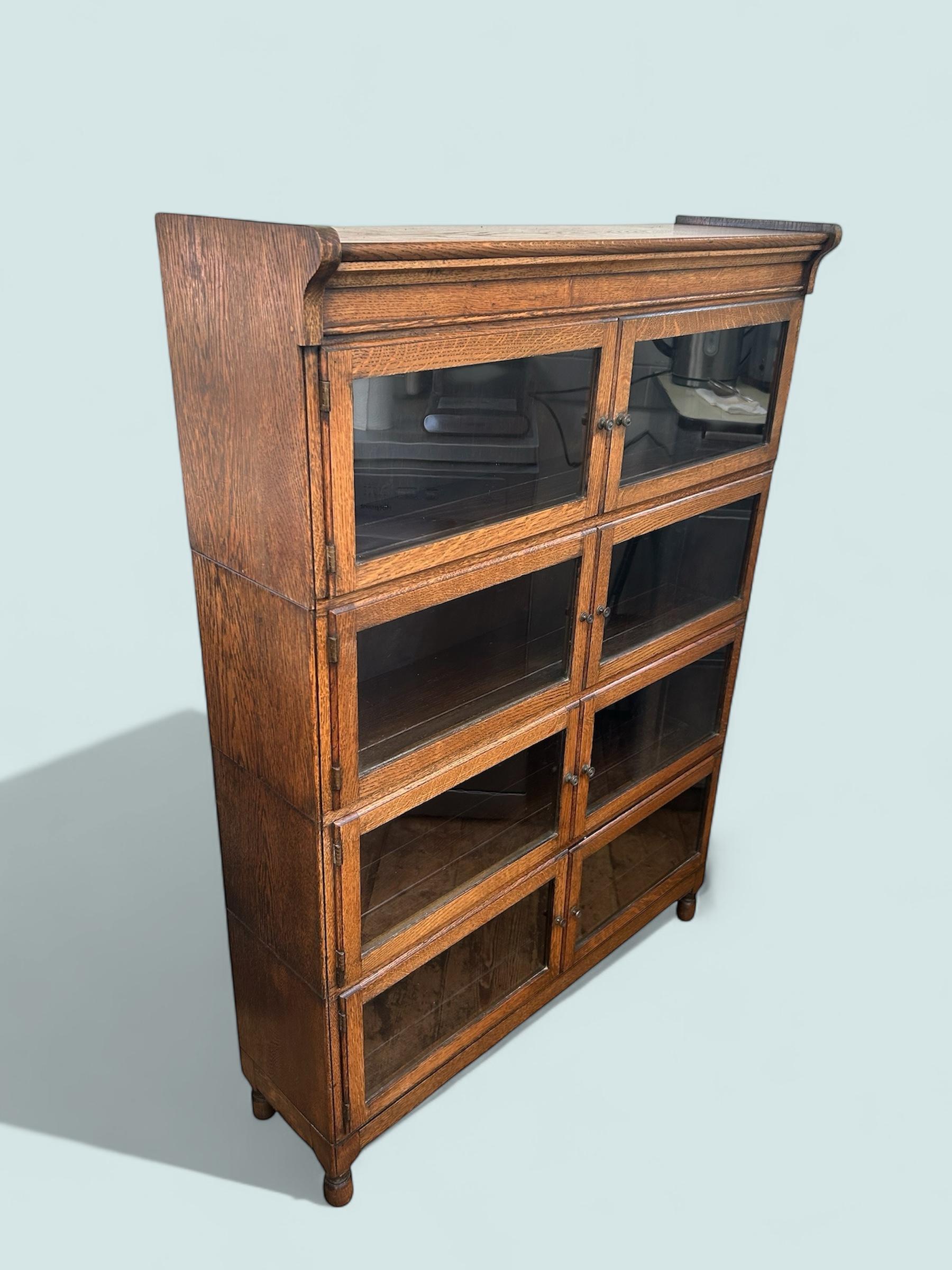 Minty of Oxford, libreria in rovere, modulare e smaltata del 1920 circa. Questa libreria inglese, in stile Arts and Crafts, si divide in quattro sezioni per essere trasportata facilmente. Ogni sezione ha due porte gemelle con i pomelli originali in