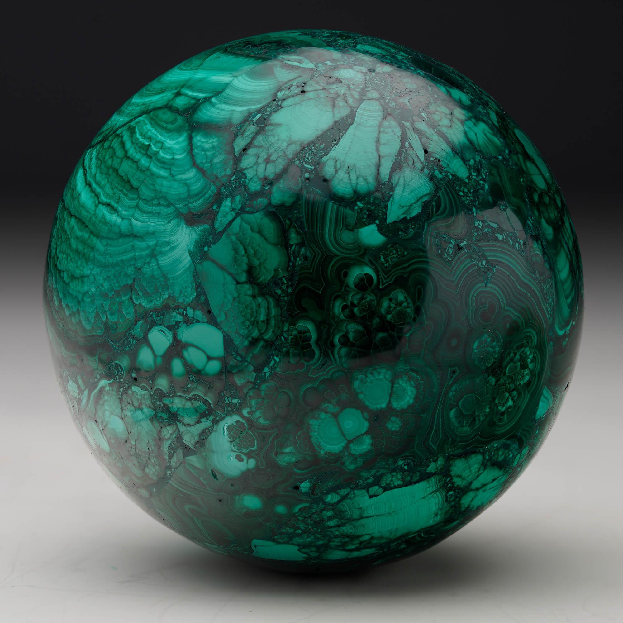 Crafted from solid, natural Malachite, this sizable hand-polished crystal sphere is a work of art: foregrounding the stone’s signature swirling green banding, contrasting bullseyes, and rich, natural luster. A mesmerizing décor piece.

Malachite has