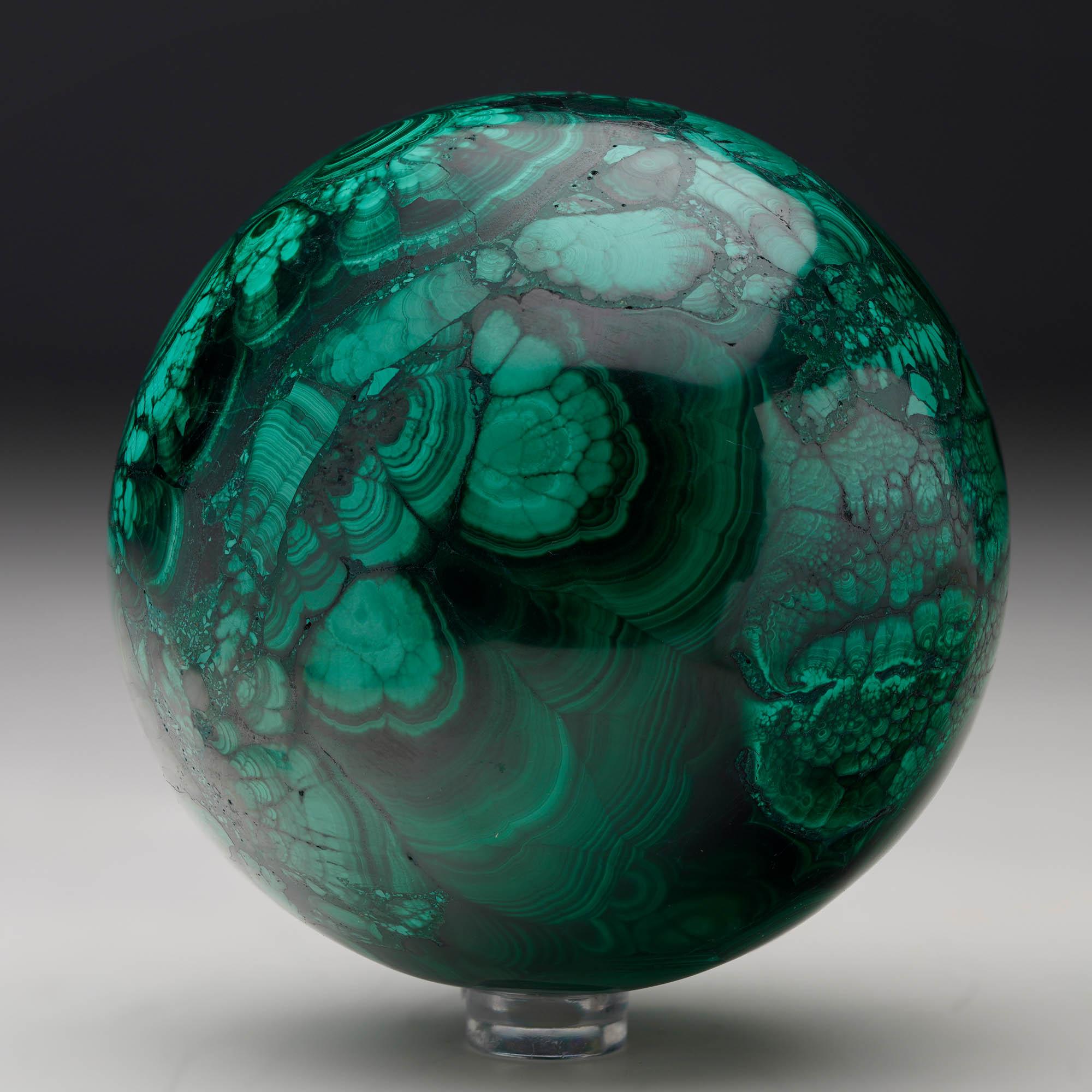 Crafted from solid, natural Malachite, this sizable hand-polished crystal sphere is a work of art: foregrounding the stone’s signature swirling green banding, contrasting bullseyes, and rich, natural luster. A mesmerizing décor piece.

Malachite has