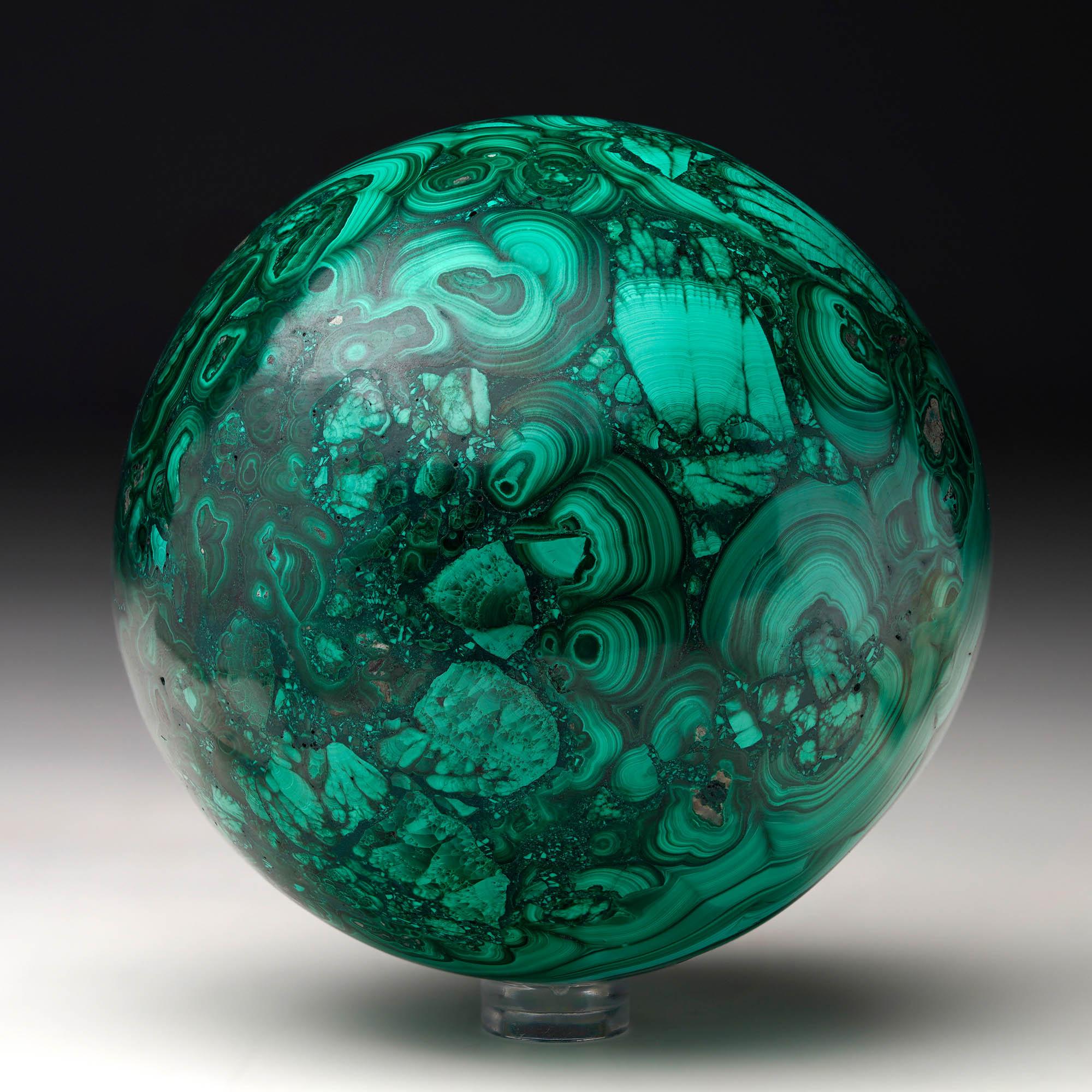 Crafted from solid, natural Malachite, this sizable hand-polished crystal sphere is a work of art: featuring a prominent, beautifully-defined bullseye, the Malachite's signature swirling green banding, contrasting bullseyes, and rich, natural luster