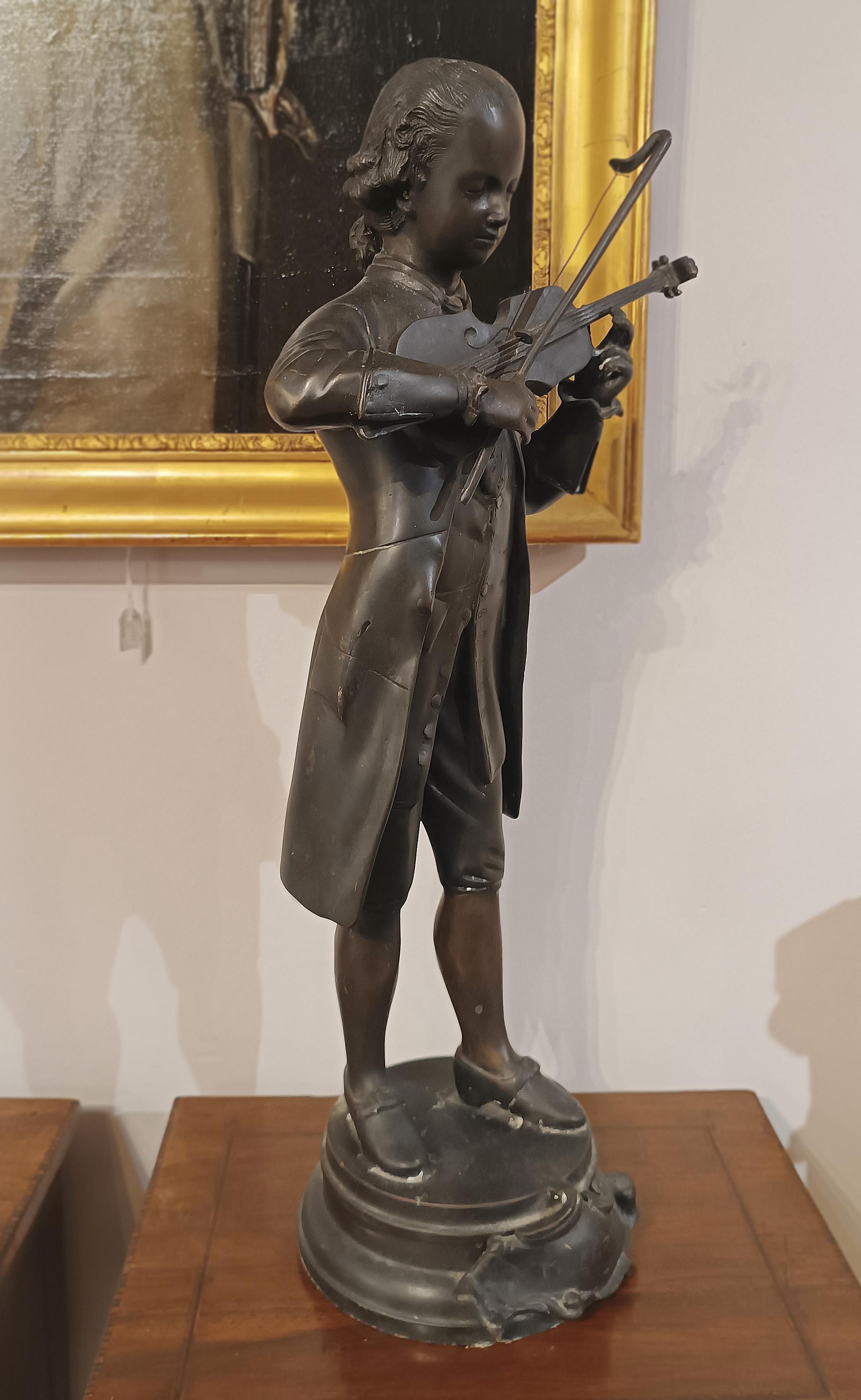 Beautiful lost-wax cast bronze sculpture depicting a young Mozart. The famous composer and musician is depicted wearing typical eighteenth-century clothing, wearing trousers, boots, a bodice and a knee-length jacket, as can be seen and noted in his