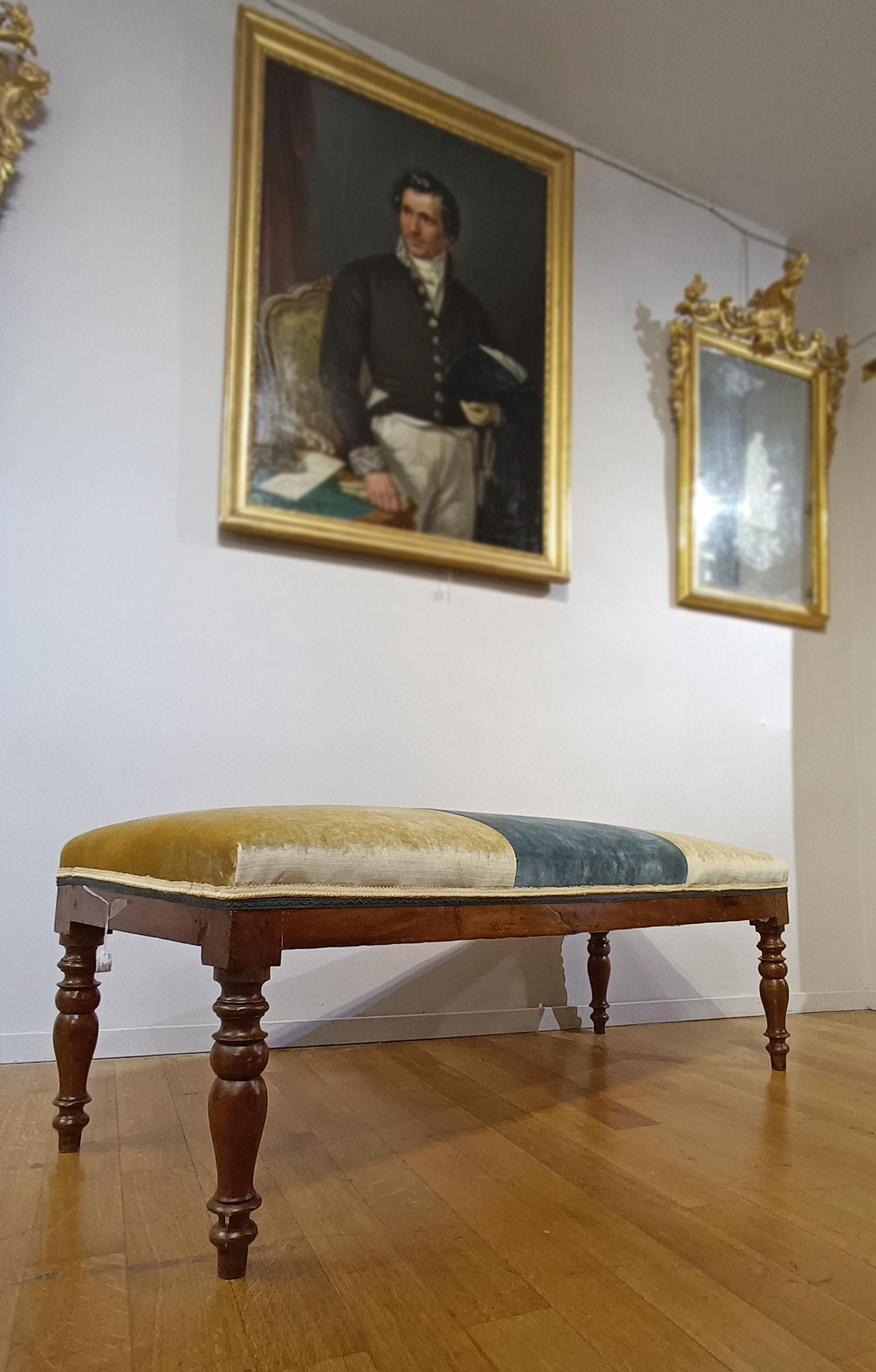 Elegant small bench in solid walnut. The bench stands out for its turned legs that add a touch of elegance to its simple and refined line. The seat is extremely comfortable, enriched with padding and covered in three-compartment fabric in gold and