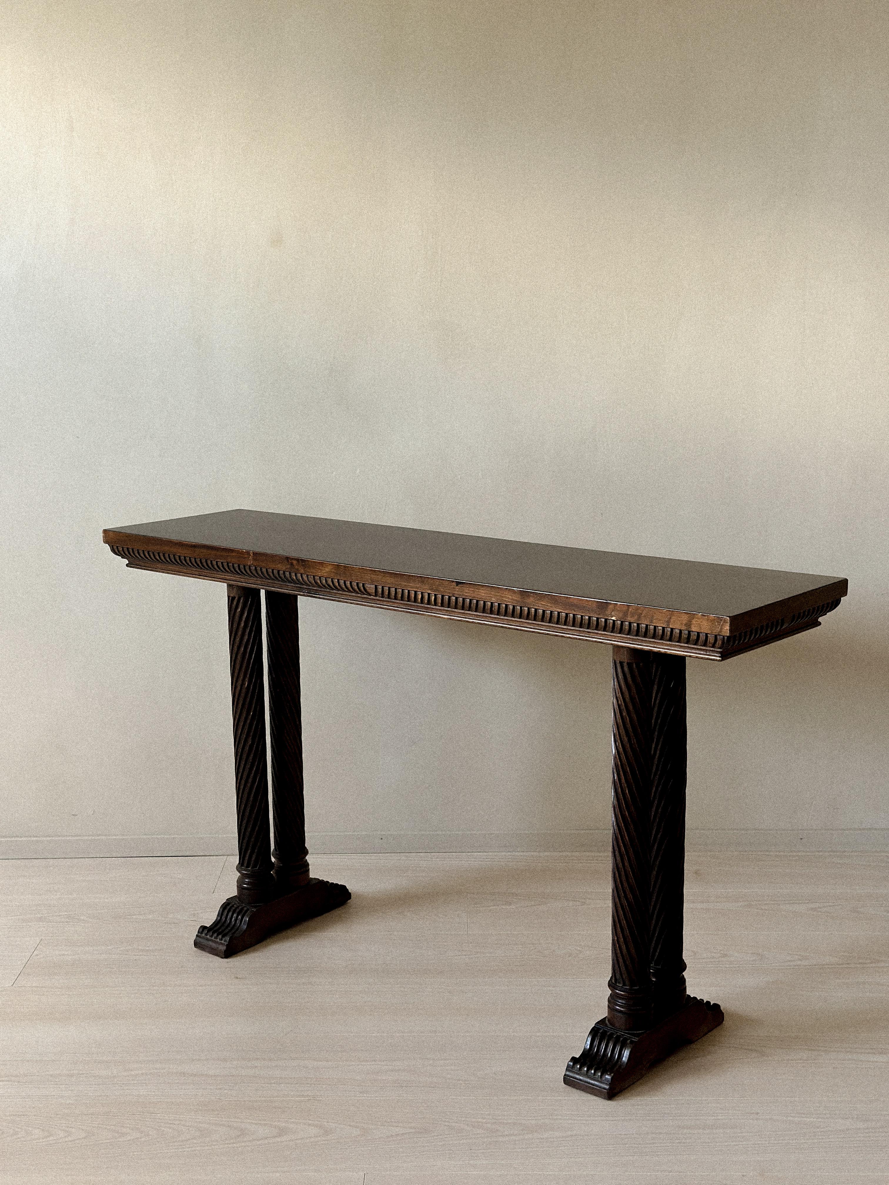 Console table with fluted apron and twisted column legs resting on carved footed bases. Dark stained wood with rich patina. Made in Spain, circa 1930s. Wear consistent with age and use.










