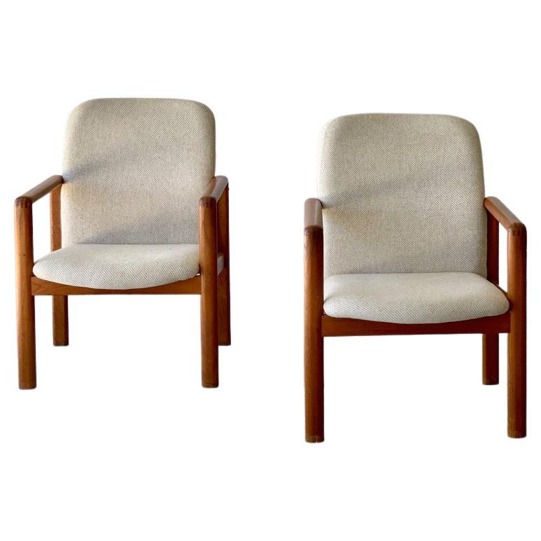 A pair of teak wood arm chairs by Benny Linden. Upholstery original to chairs, in parchment color in a cross hatch textured fabric.