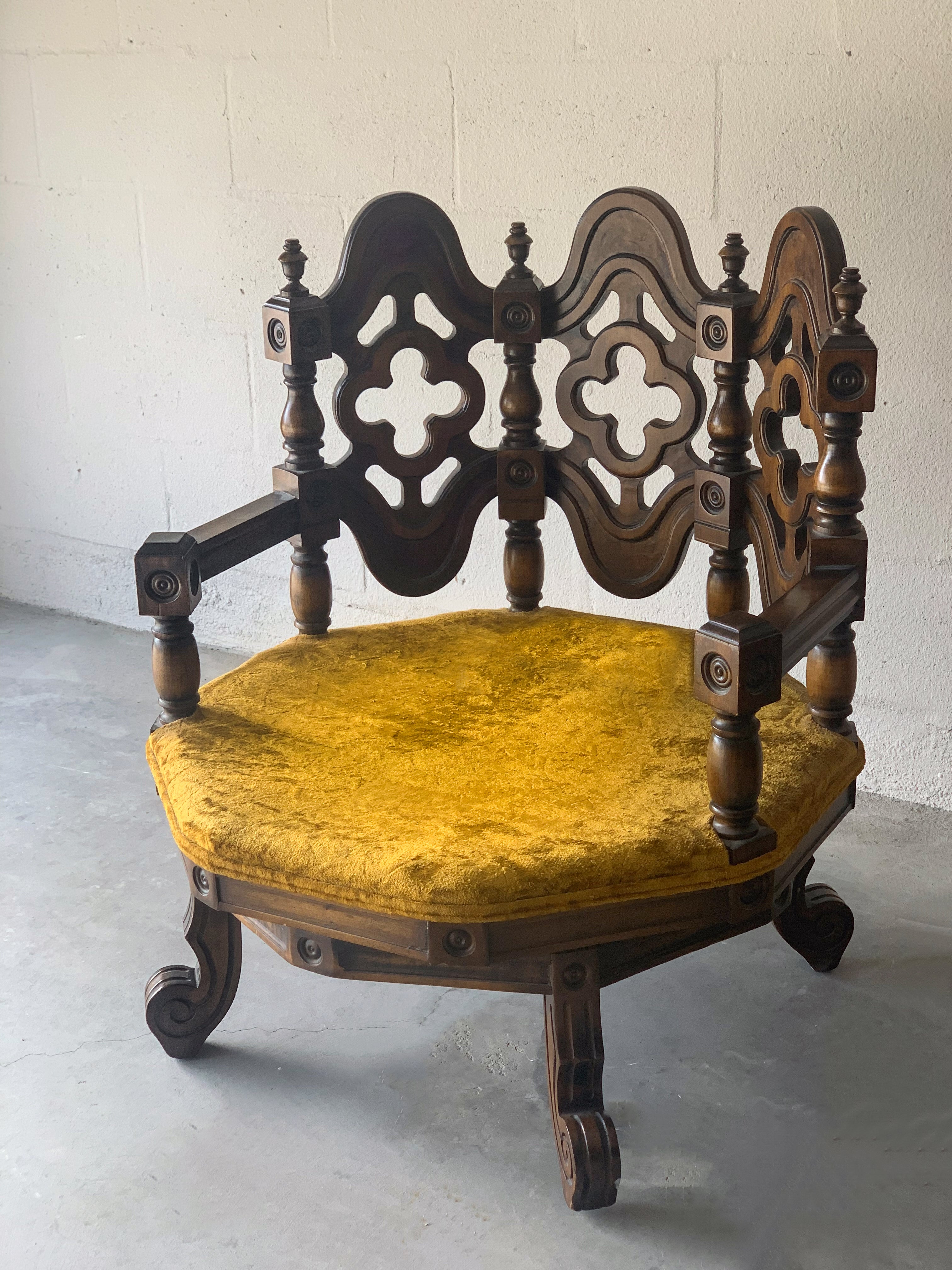An intricately carved swivel chair from the 20th c. Base rotates a full 360 degrees. Chair is highlighted by a sculptural back, hand-crafted in gothic motifs. Crushed velvet upholstery is original to the chair and are removable. Chair makes a
