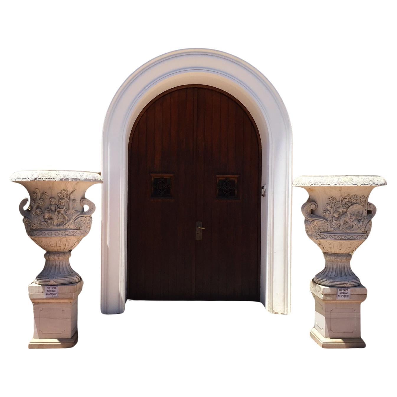 Large pair Carrara Marble Urns with Pedestals, pedestals are later made for the urns, each one carved with cherubs with deer and other side cherubs hunting an eagle.