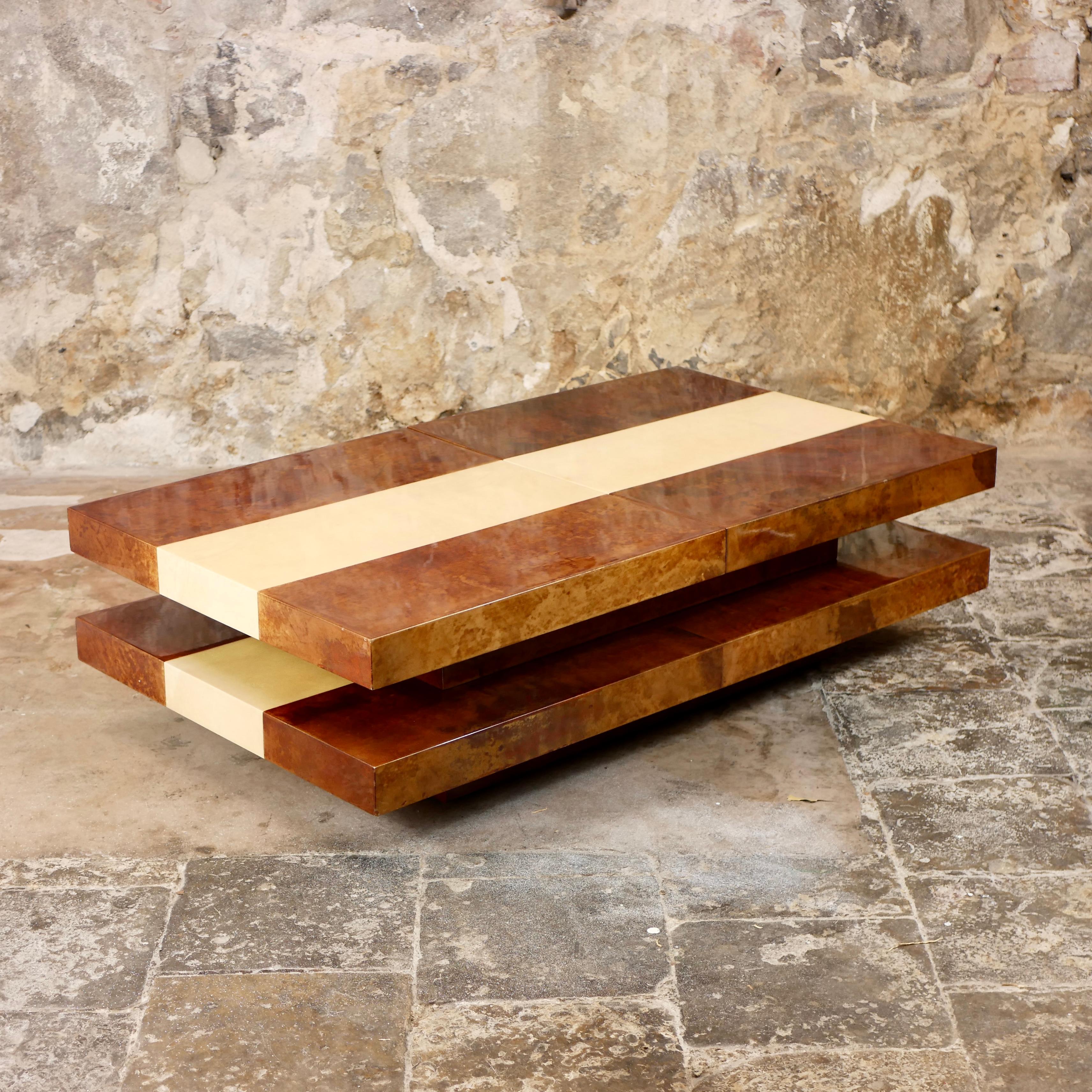 Gorgeous coffee table by the Italian master Aldo Tura, made in Italy in the 1970s.
Large coffee table with two-tiered wooden base covered with two-tones goatskin parchment, entirely lacquered, which reflects perfectly the light. 
The top slides and