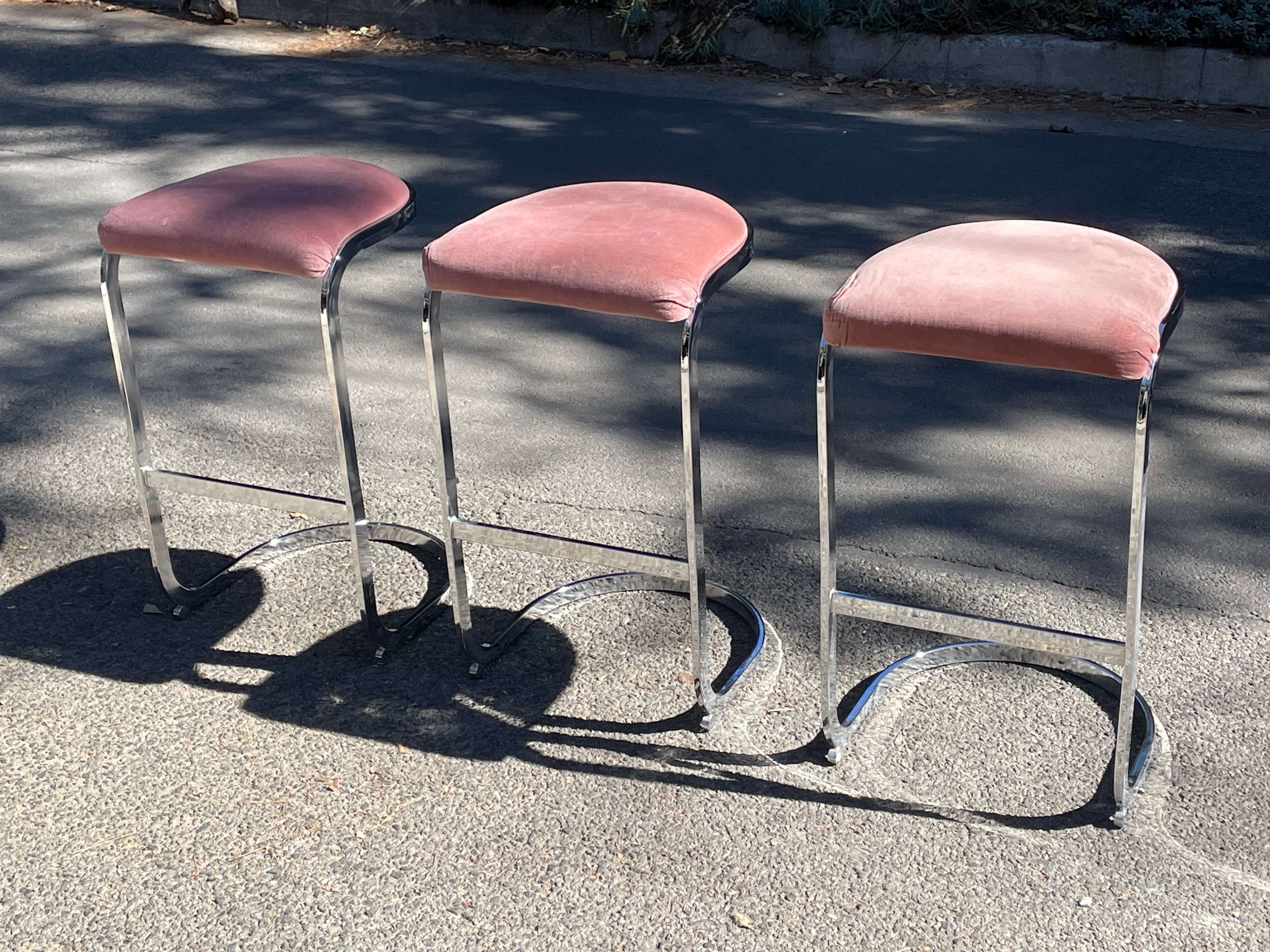 Set of three sculptural chrome cantilevered bar stools by Milo Baughman. 

Great lines on these bar stools. Clean and simple design. The chrome really plays well off the blush.

Chrome flat bar bases and the fabric are both in very good vintage