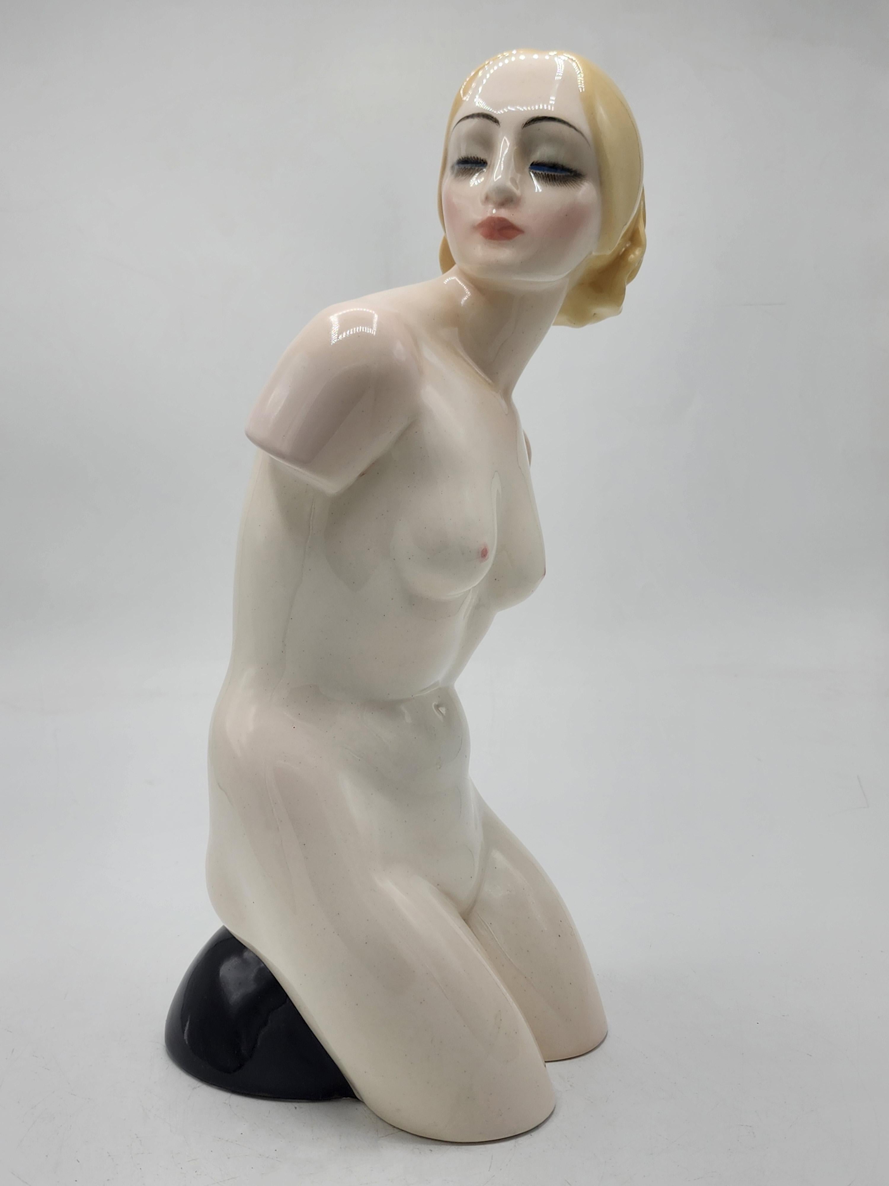 Figurina in porcellana italiana Essevi Torino
Questo pezzo presenta una figura femminile inginocchiata, realizzata in porcellana con una finitura liscia e lucida. La forma complessiva è stilizzata, con linee fluide che definiscono il corpo. La