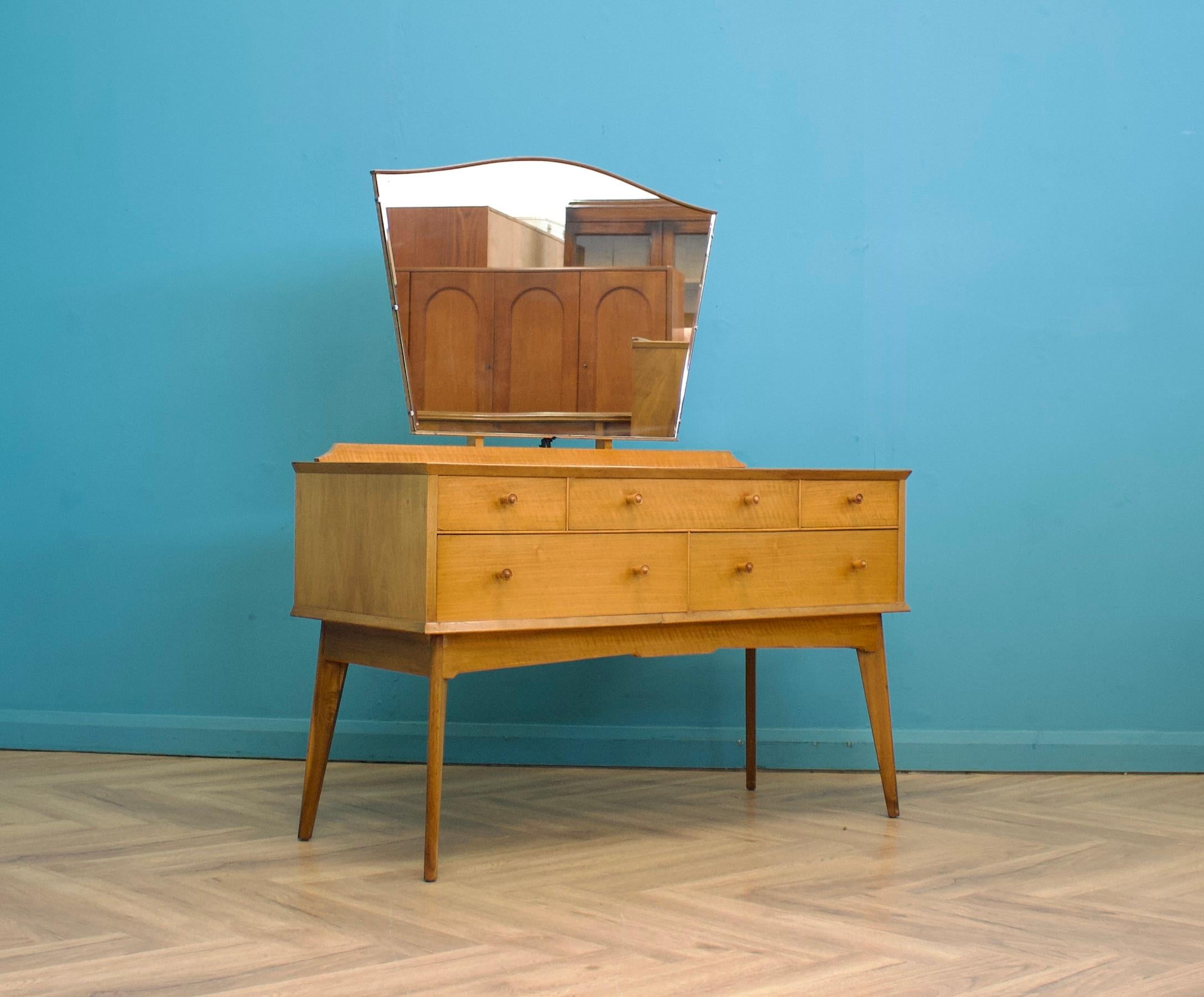 A mid-century walnut dressing chest from Alfred Cox, circa 1950s.
 
The dressing table includes five drawers and a fixed mirror
 
Height to the top of the mirror is 139 cm 
 
The matching wardrobe and chest of drawers are available to buy on
