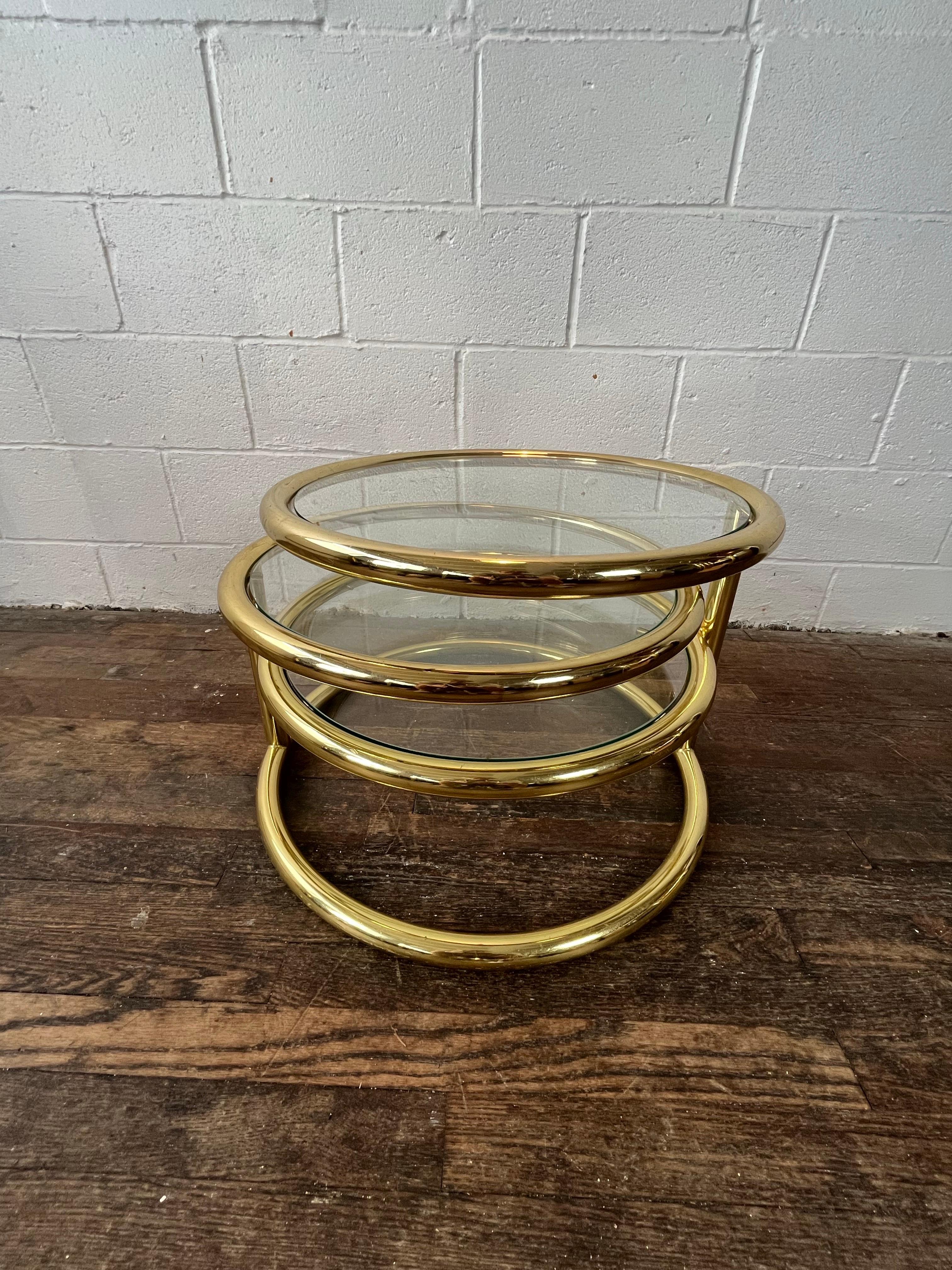 Gorgeous three-tier swivel coffee table with a high shine brass finish in the style of Milo Baughman, 1970's.

An endlessly versatile table, the top two tiers smoothly swivel to create desired position allowing for a multitude of configurations to