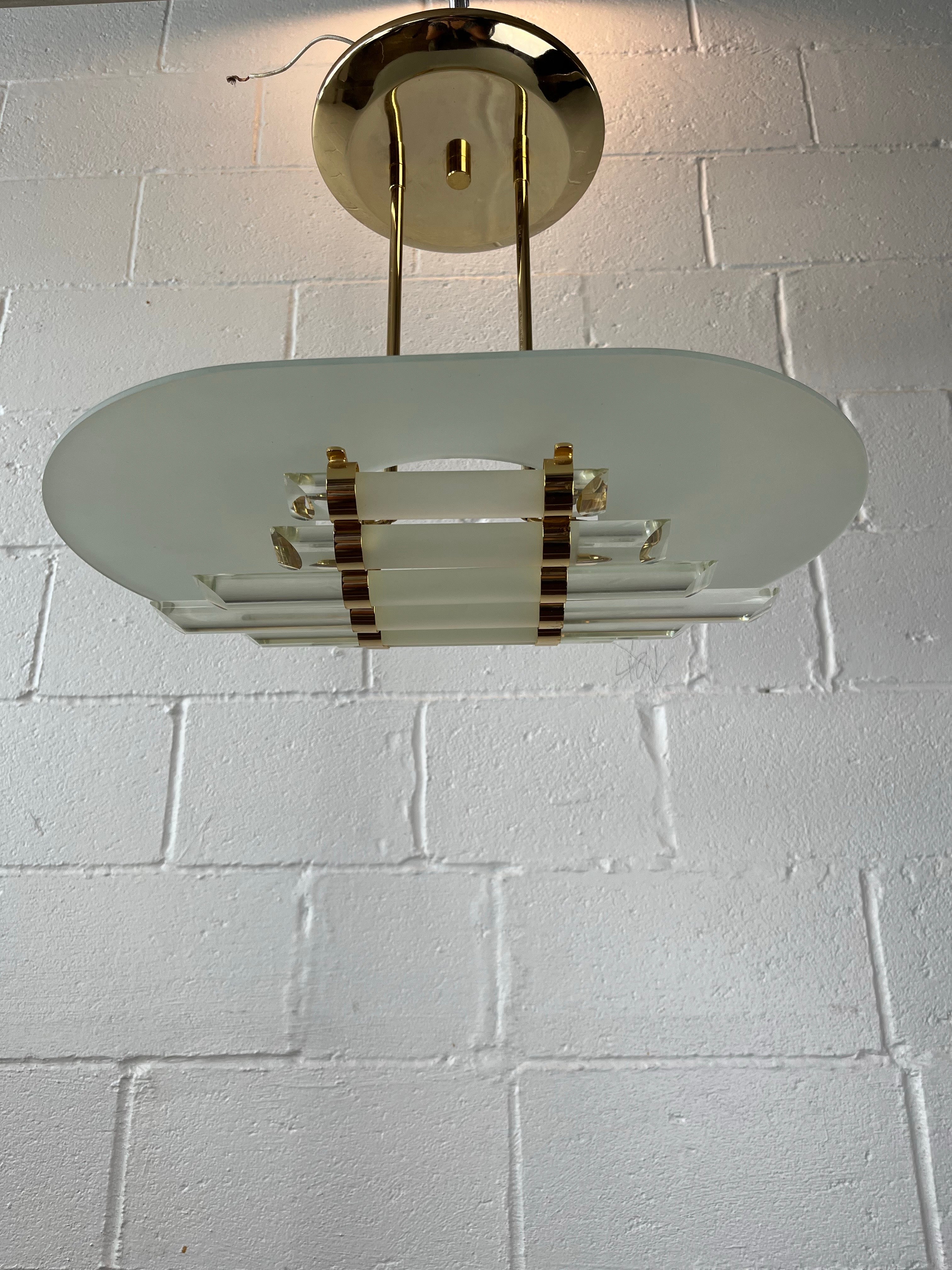Lustre de style gratte-ciel moderniste du milieu du siècle avec des tiges de verre et des ferrures en laiton dans le style de Sciolari. Sept baguettes en verre demi-rond clair et dépoli aux extrémités biseautées qui sont regroupées dans une forme
