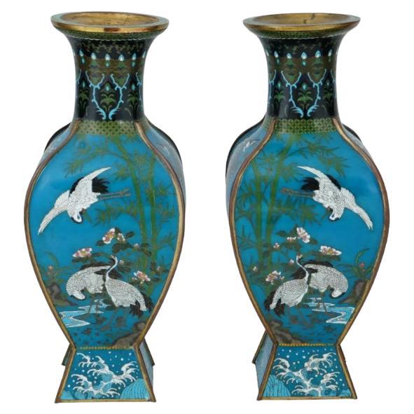 A pair of antique Japanese Meiji period facet cloisonne vases, featuring captivating bird motifs. Their substantial size and ribbed design make them standout pieces. Adorned with intricate bird motifs meticulously crafted in cloisonne, these vases