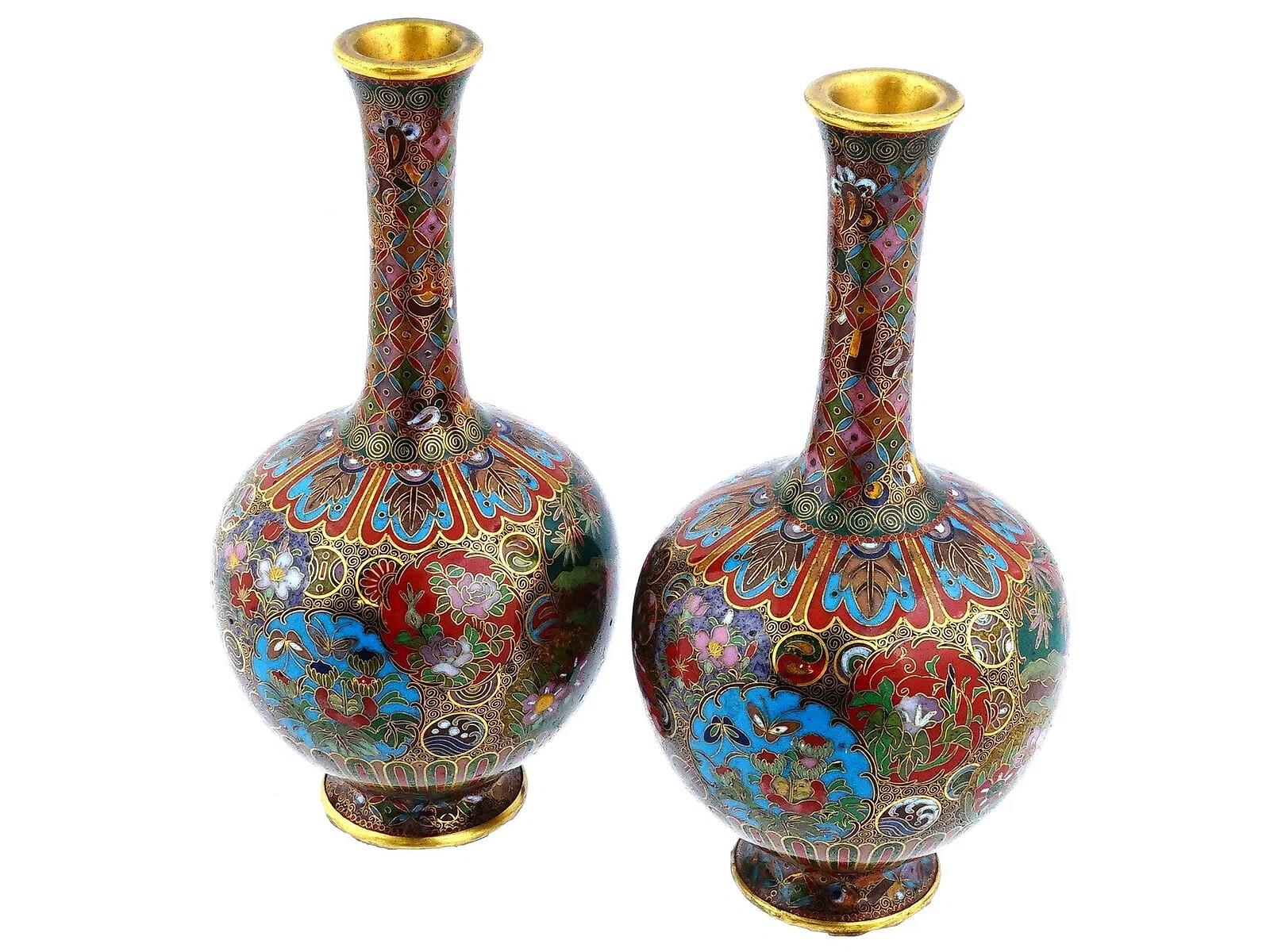 A pair of Japanese cloisonne enameled brass vases. They feature a narrow neck, rounded body, and are decorated with an intricate pattern of floral designs in various colors, and gilt accents. Antique and Vintage Asian and Oriental Enamel Vases,