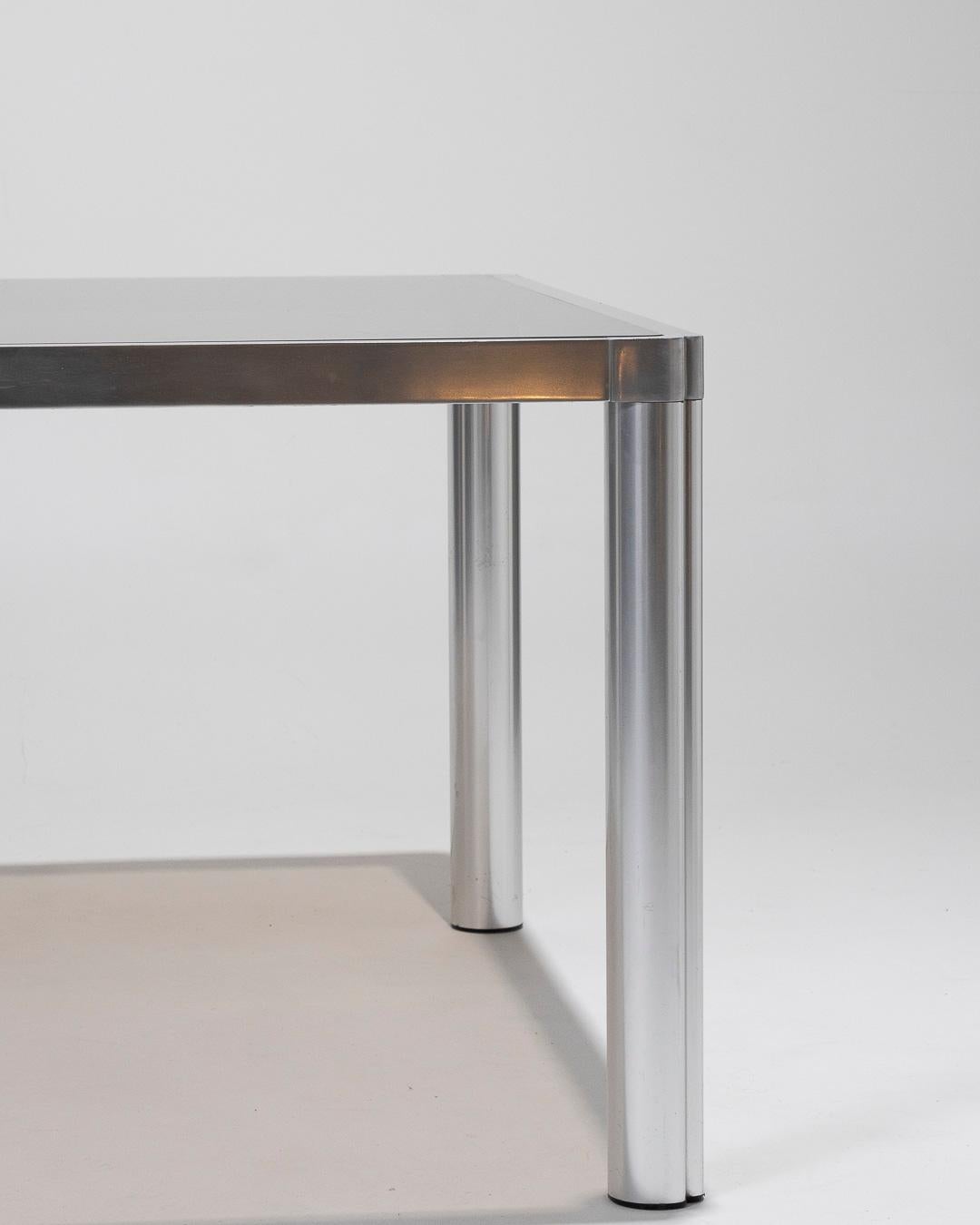 Square Dining Table with Smoked Glass Top and Thick Aluminum Frame, combining both modernity and sophistication. The smoked glass top offers a subtle transparency, creating a sense of space while highlighting the robustness of the frame. The tapered