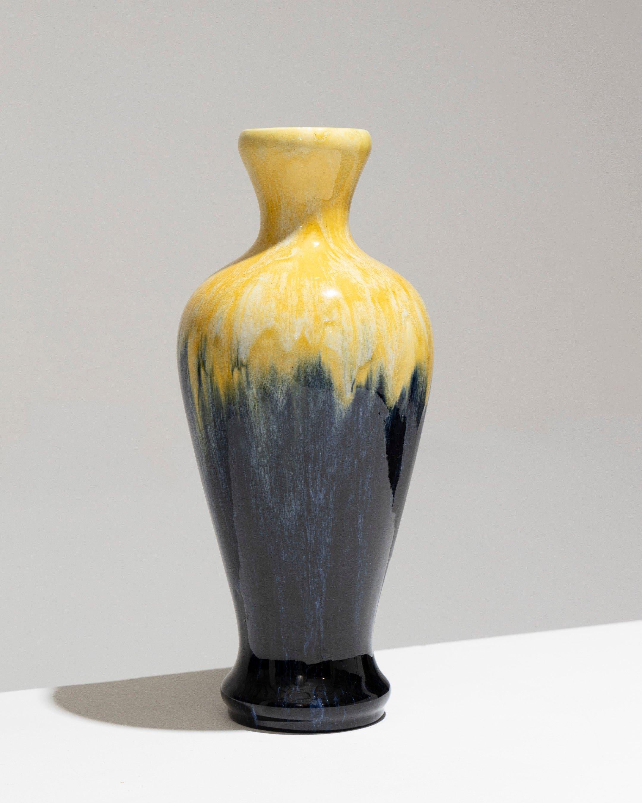 Vase en faïence à corps oblong sur piédestal, Manufacture Boch Frères Keramis, années 1930. Le vase présente un col évasé et est décoré d'un motif flammé jaune jusqu'à l'épaule, suivi d'un décor bleu aux tons marins sur le corps. L'intérieur est