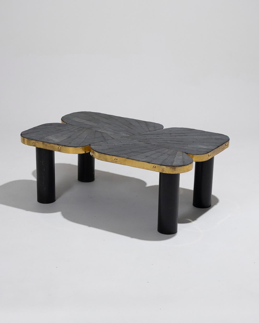 Coffee table in slate and brass marquetry. Unique piece, produced by the French artist of Serbian origin Marko. Irregular and organic in shape, the tray is set with slate and surrounded by a large brass band. The four cylindrical feet are in