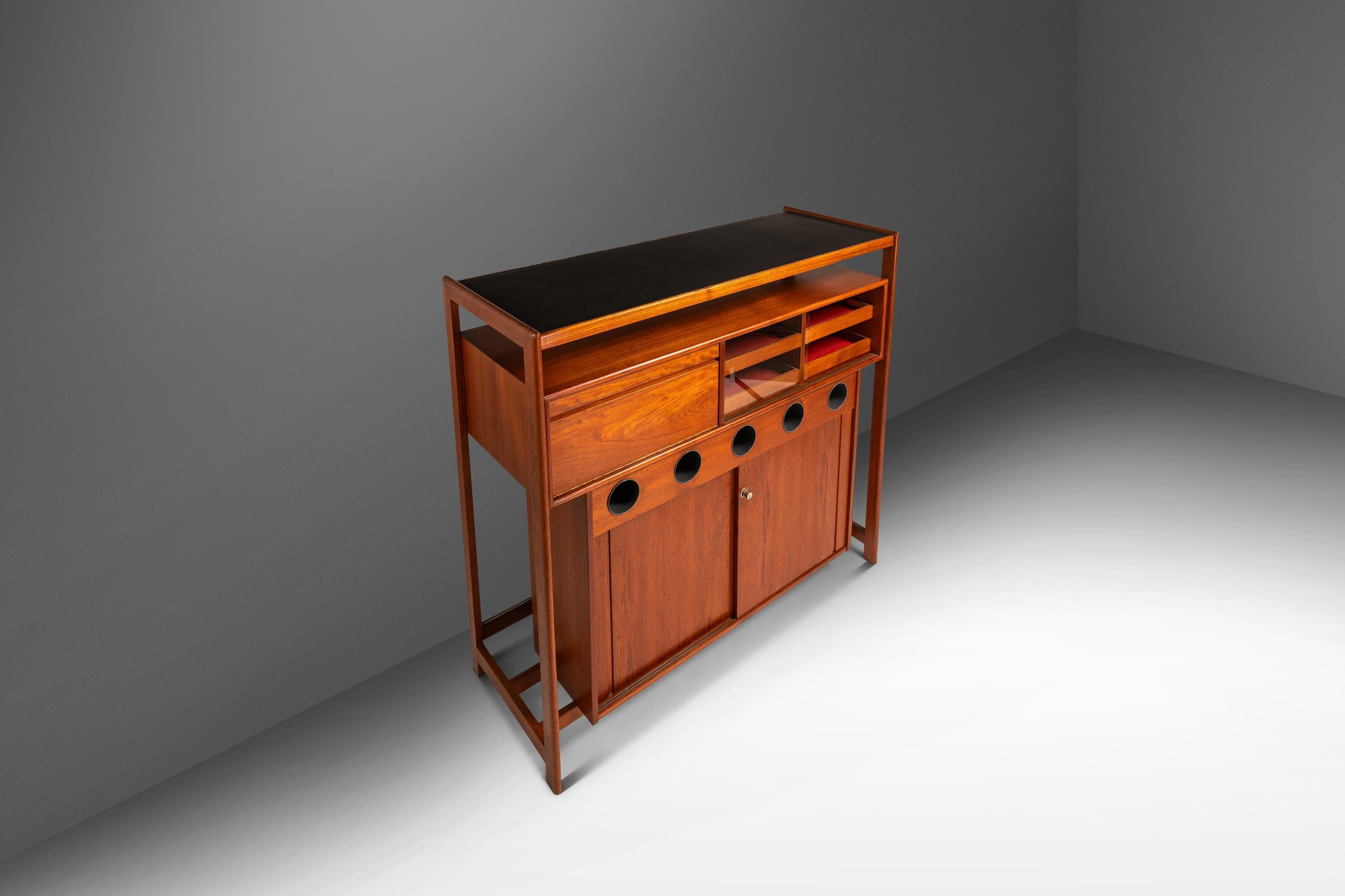 Introducing a rare Danish-made dry bar designed by the incomparable Knud Bent for Dyrlund. This sculptural and highly functional dry bar, is a refined example of Danish craftsmanship at its finest. Constructed from a mix of solid and veneered