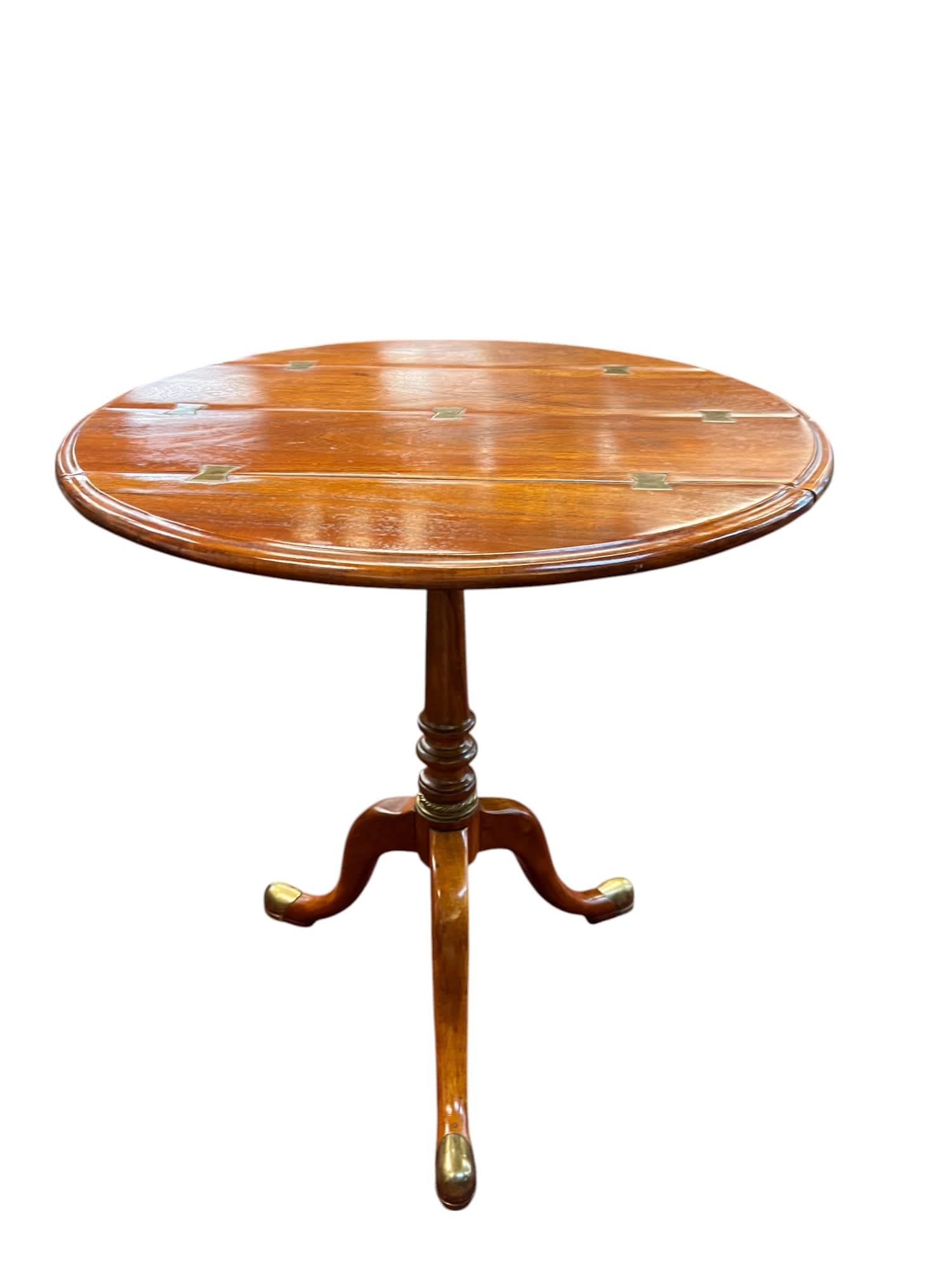 Crafted by renowned furniture house Theodore Alexander, this pedestal table draws inspiration from late Georgian to early Regency design. The round top is composed of individually pieced wood blanks, visually joined by inlaid brass strips that