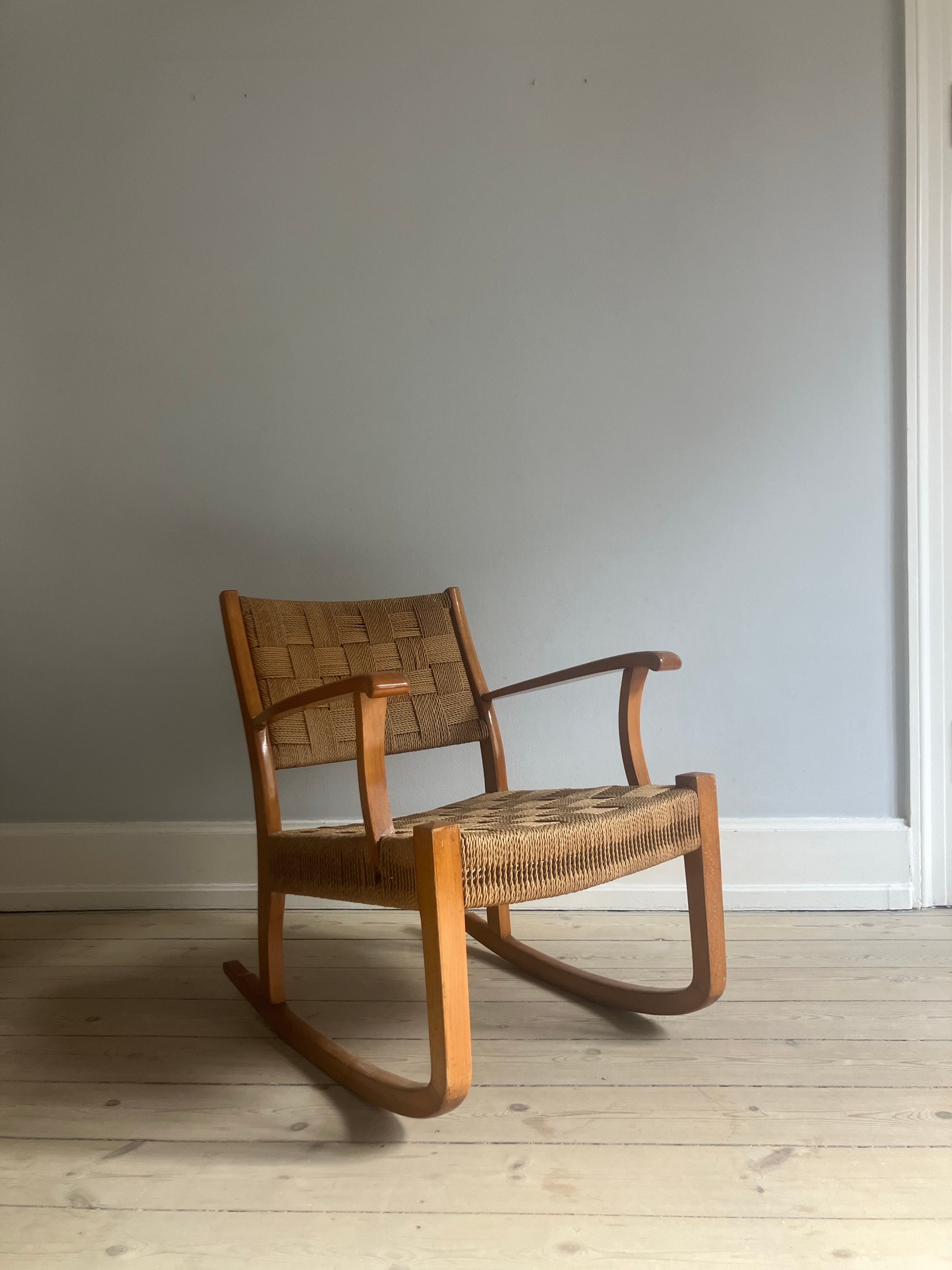 Frits Schlegel Fauteuil à bascule en osier, en hêtre laqué et avec un tressage de papier serré et intact dans l'assise et le dossier. 

La chaise a été conçue dans les années 1940 au Danemark  et est produite par Fritz Hansen. Ce rocking-chair est
