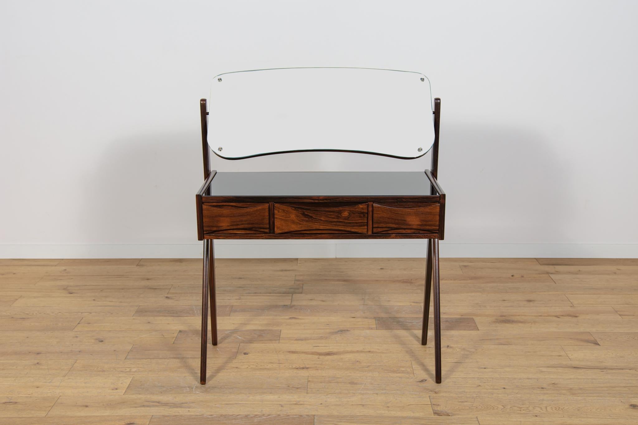 A small rosewood dressing table designed by Arne Vodder for Ølholm Møbelfabrik. The dressing table has three drawers. There is an adjustable mirror in the frame above the dressing table. The furniture has been completely renovated, wood has been