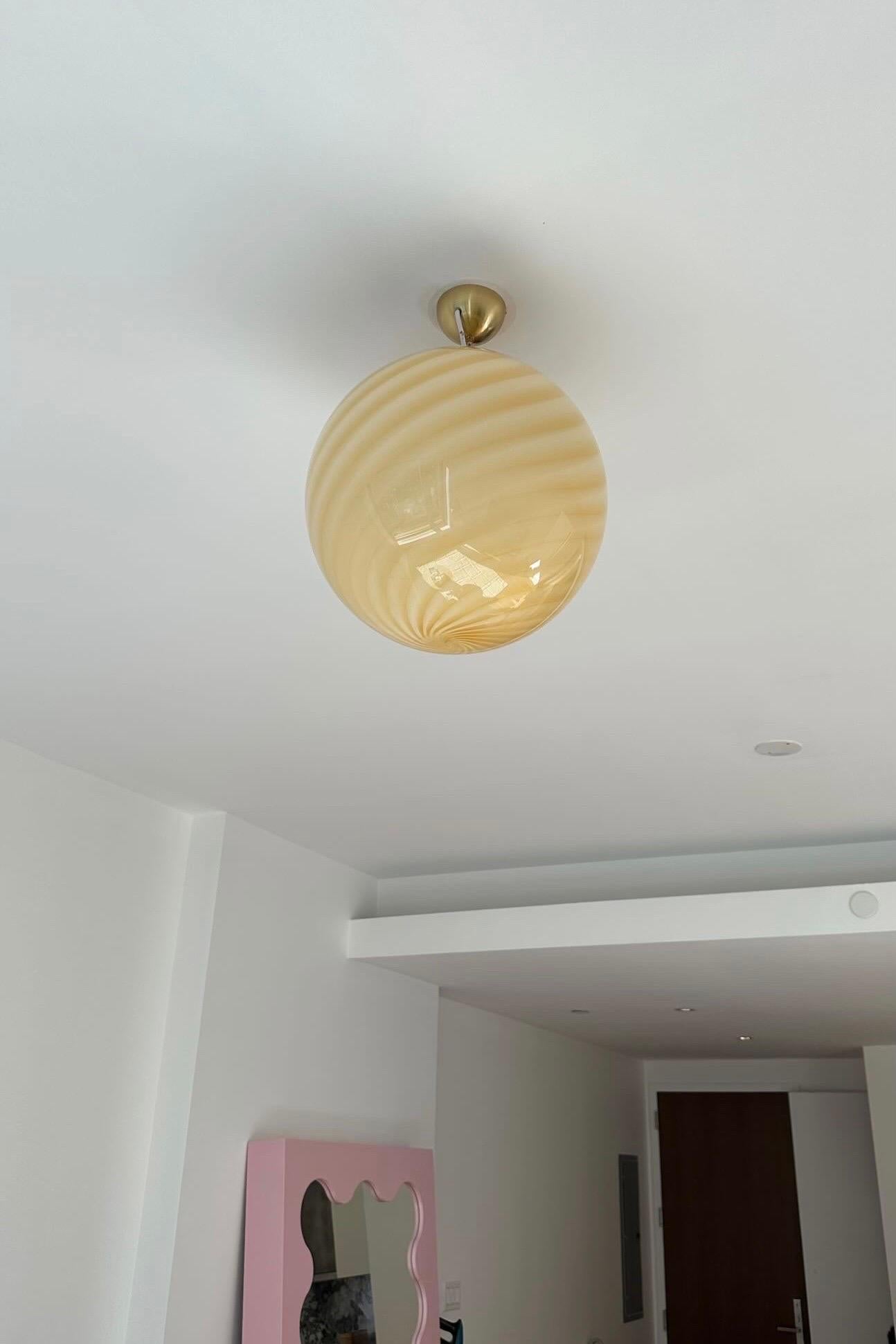 Large new Italian Murano candy pendant ceiling lamp in a beautiful soft yellow shade. Mouth-blown glass in round shape with swirl pattern. E27 socket. Comes with adjustable brass plated suspension as well as transparent cord.
Handmade in Italy.
D:40