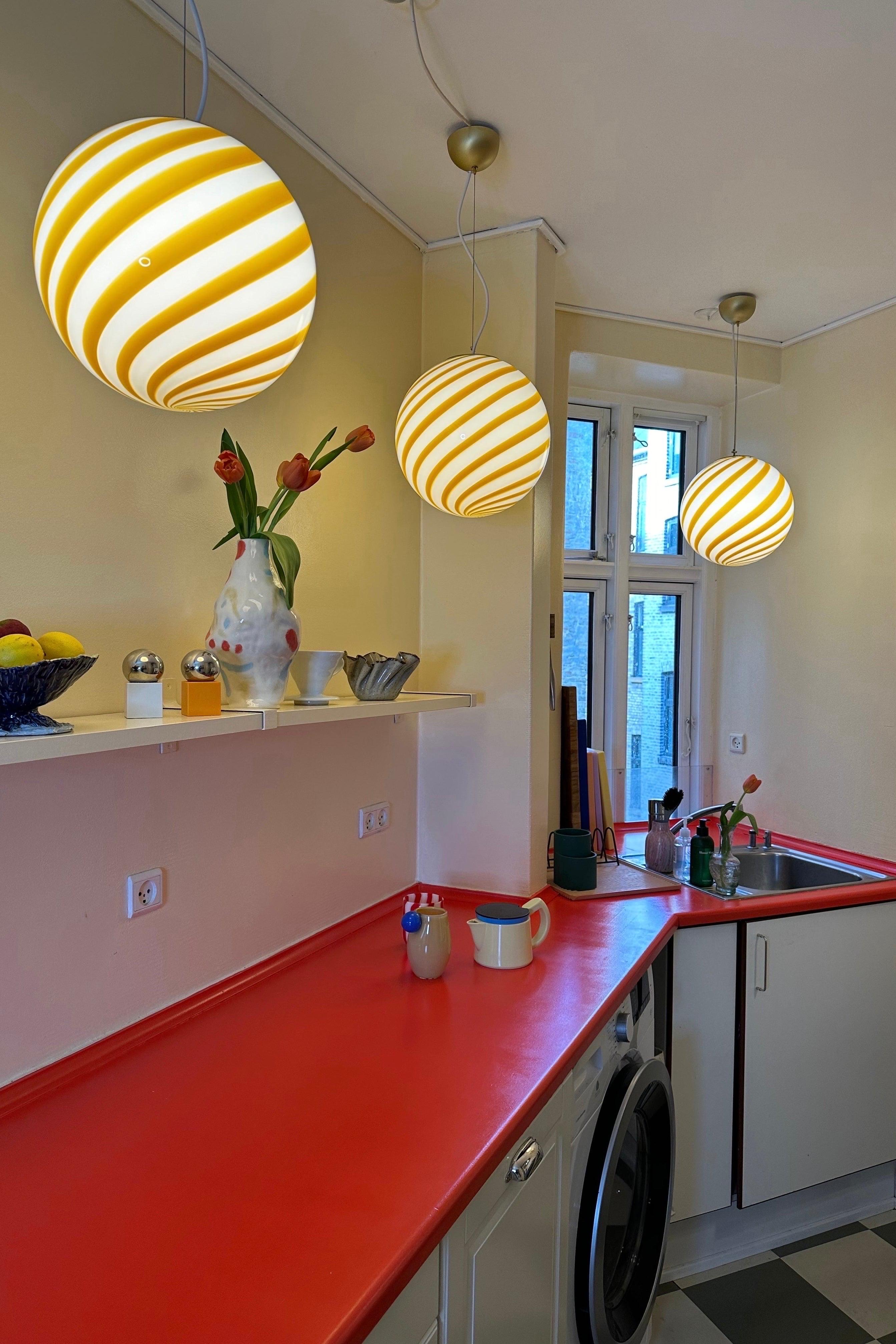 Medium Murano Vintage Candy pendant ceiling lamp in mustard yellow / white glass. Mouth-blown glass in round shape with swirl pattern. E27 socket. Comes with adjustable suspension. 
Handmade in Italy.
D:30 cm  

As it is mouth blown glass, the