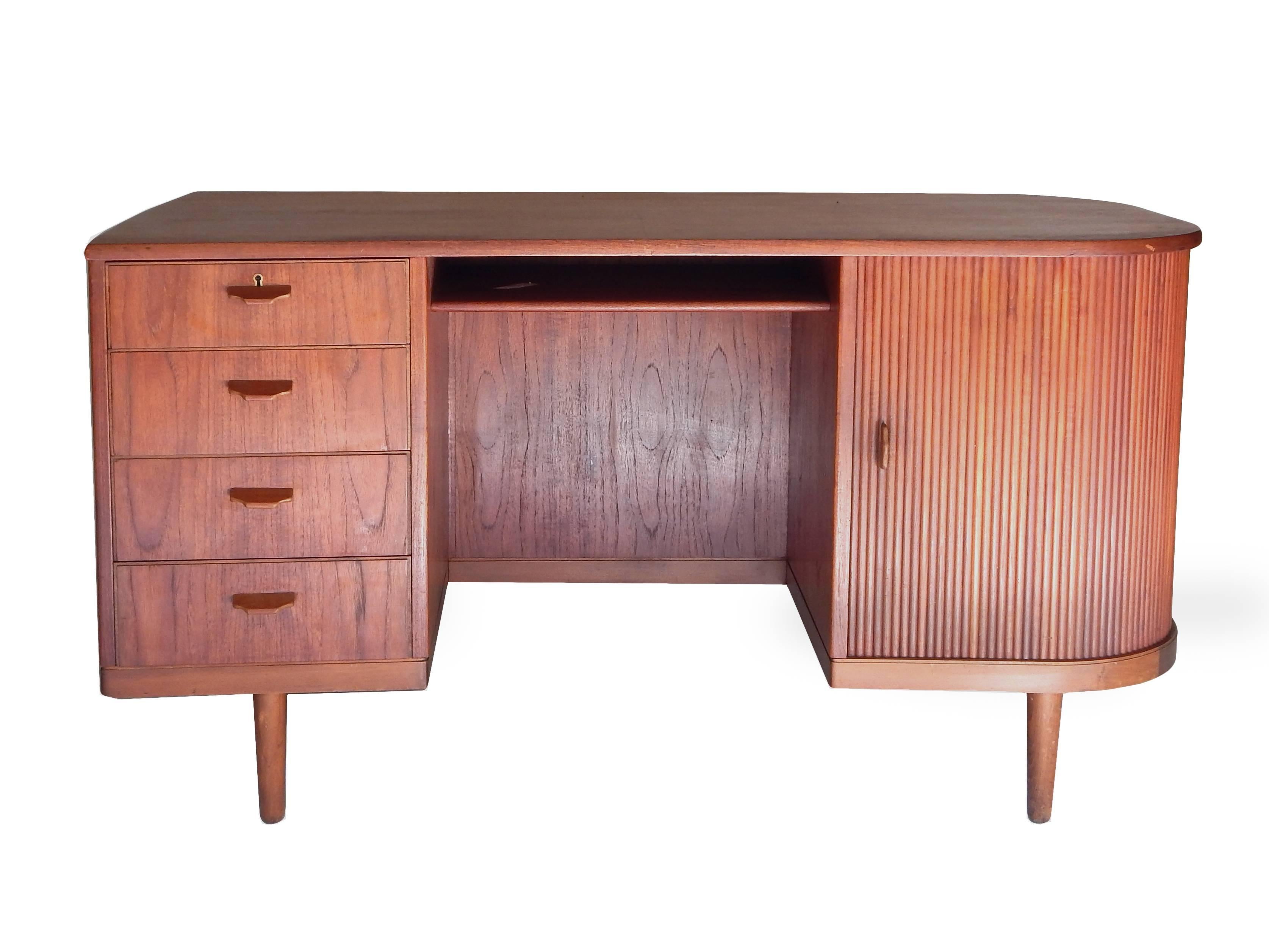 Mid-Century Scandinavian teak desk with a full bar behind a sliding tambour door. Two drawers, two wine racks and two shelves for glasses (the two glass shelves will be supplied) and space for bottles. The opposite side has one adjustable shelf so