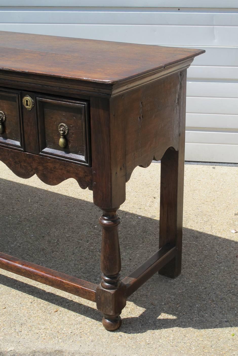 19th century oak dresser base in the Jacobean Style, with old brass hardware, front stretcher. Lovely patina.