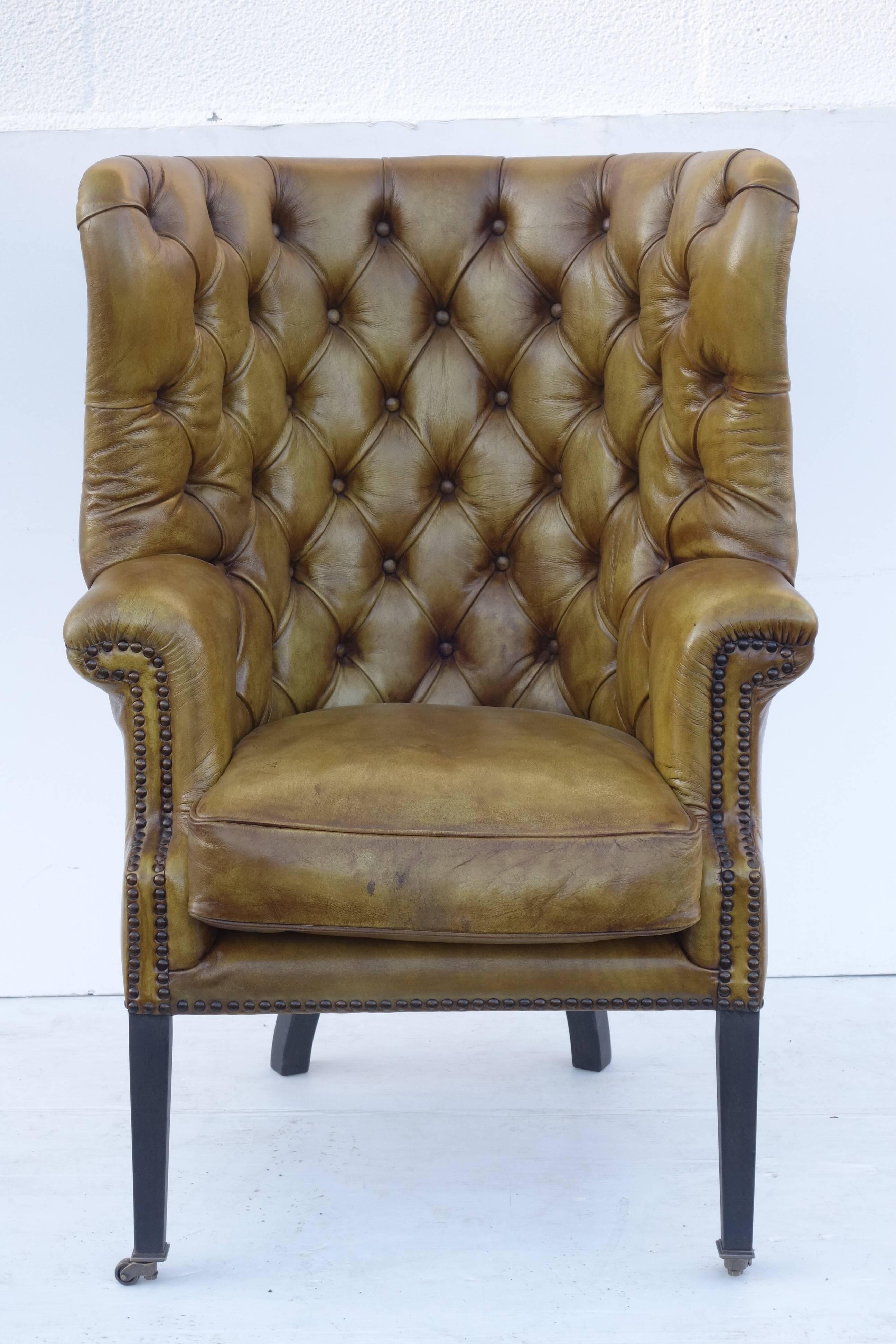 Leather upholstered armchair in vintage green with wooden legs, casters.