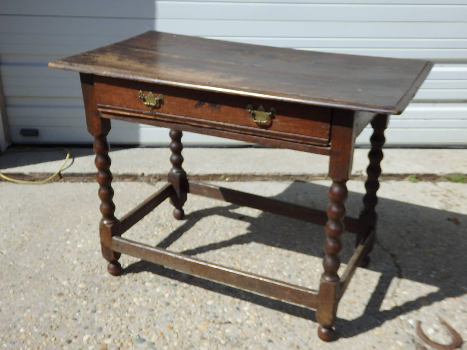 19th century English oak side table with bobbin style legs, stretcher base and original brass hardware. Some movement in the top, which is consistent with age and use.