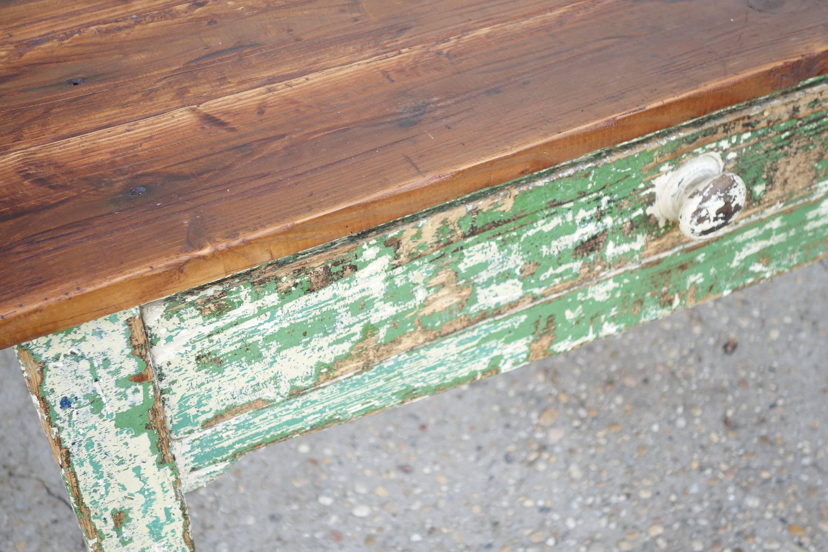 Long narrow serving table with remains of old green and white paint, two drawers and shaped front skirt. Natural waxed top.