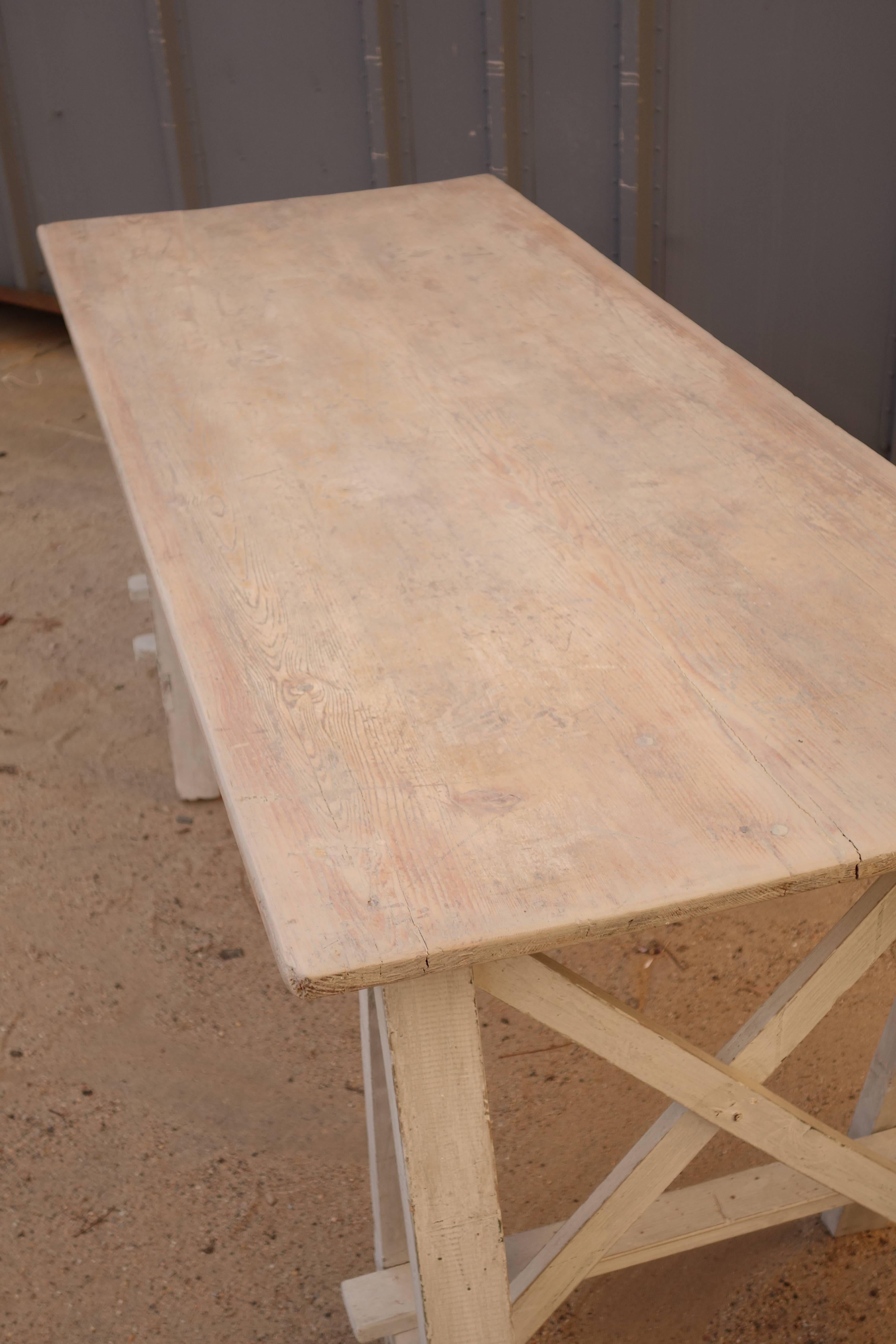 Simple work table with two white painted trestle bases, white washed top.
Measurement between legs 41