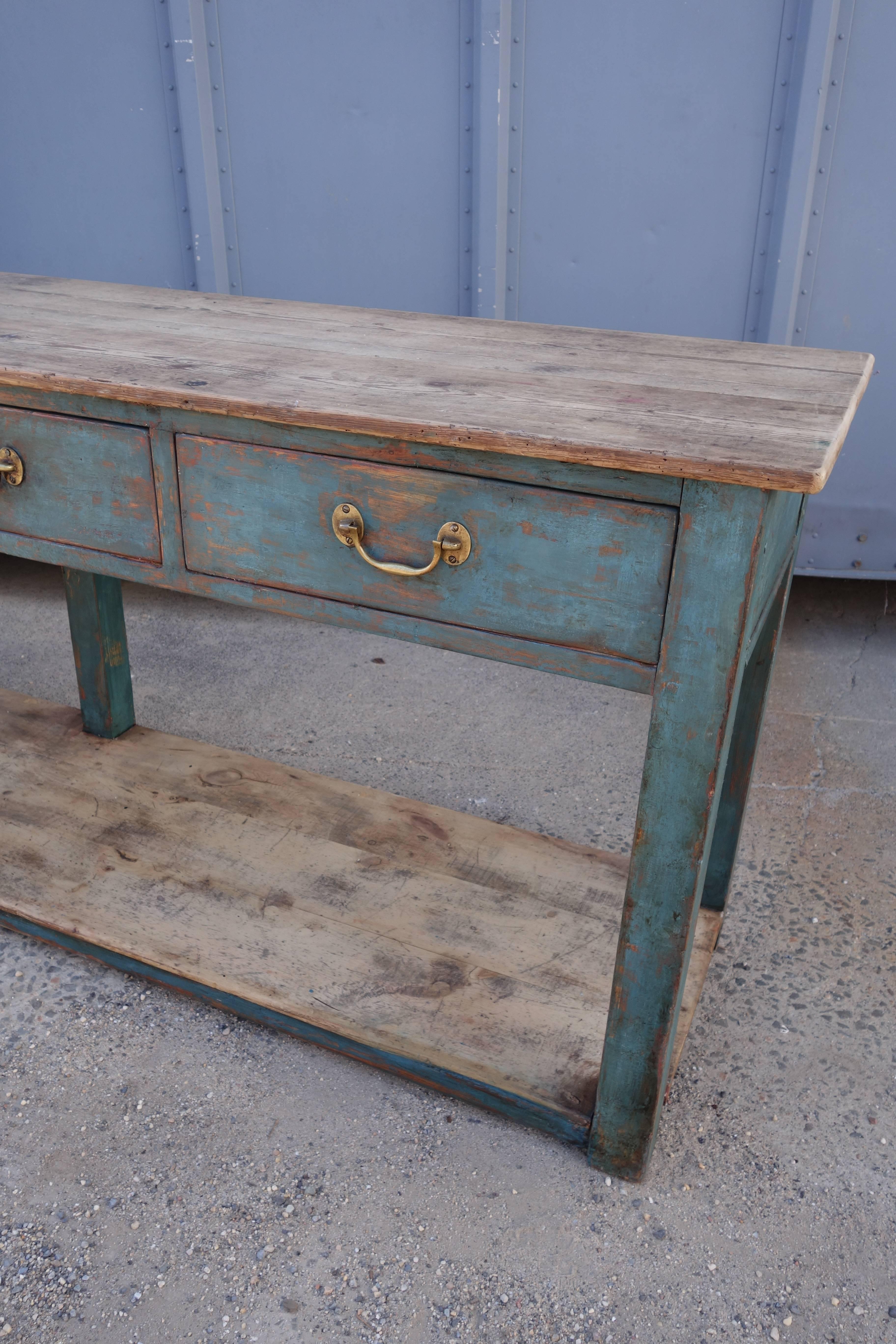 Long painted dresser base or serving table with four drawers. Natural pinewood top. Old blue green paint remains. Original brass hardware.
(Depth needs to be confirmed).
 