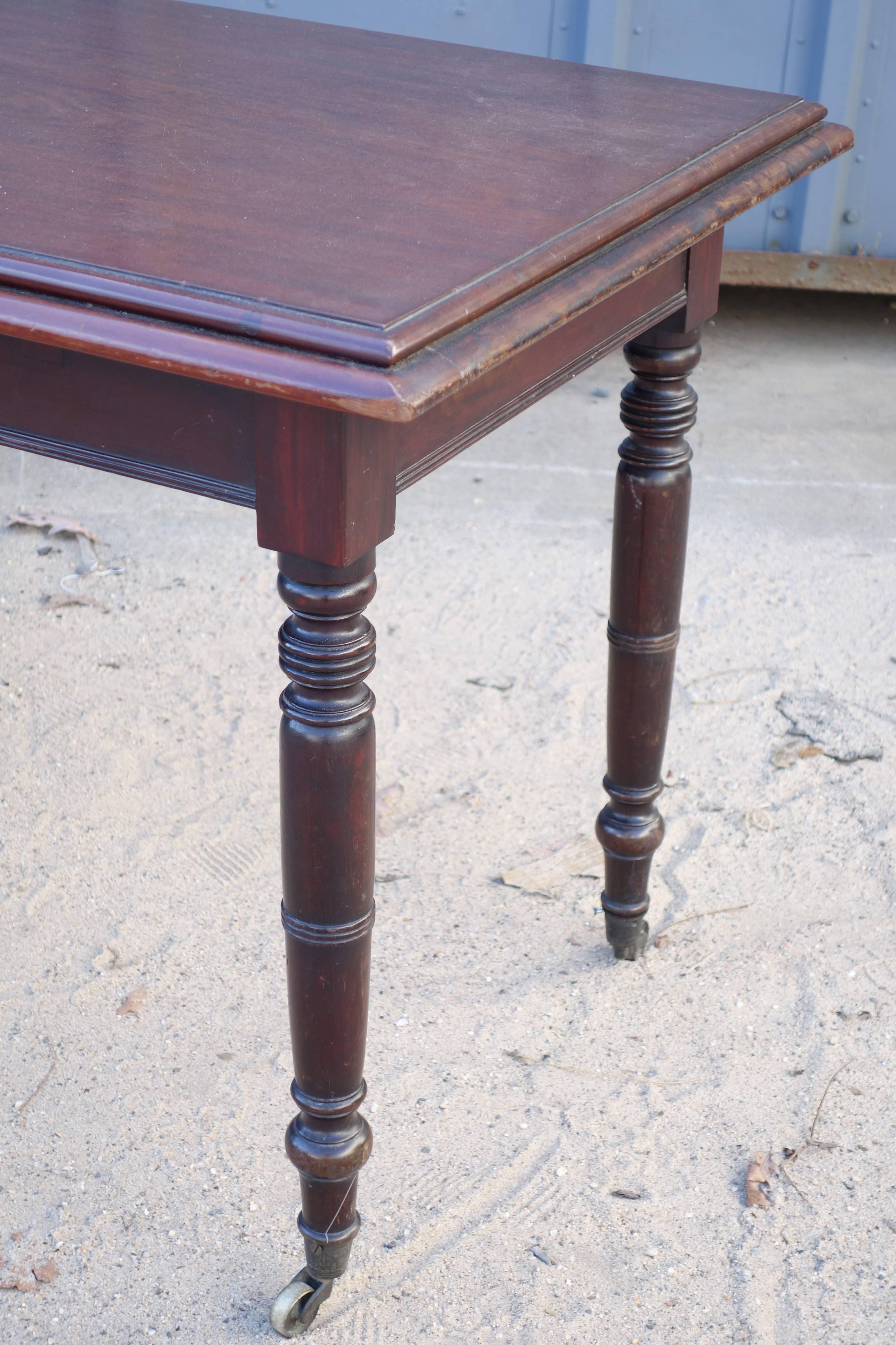 English mahogany writing table on casters, simple turned legs, nice color.