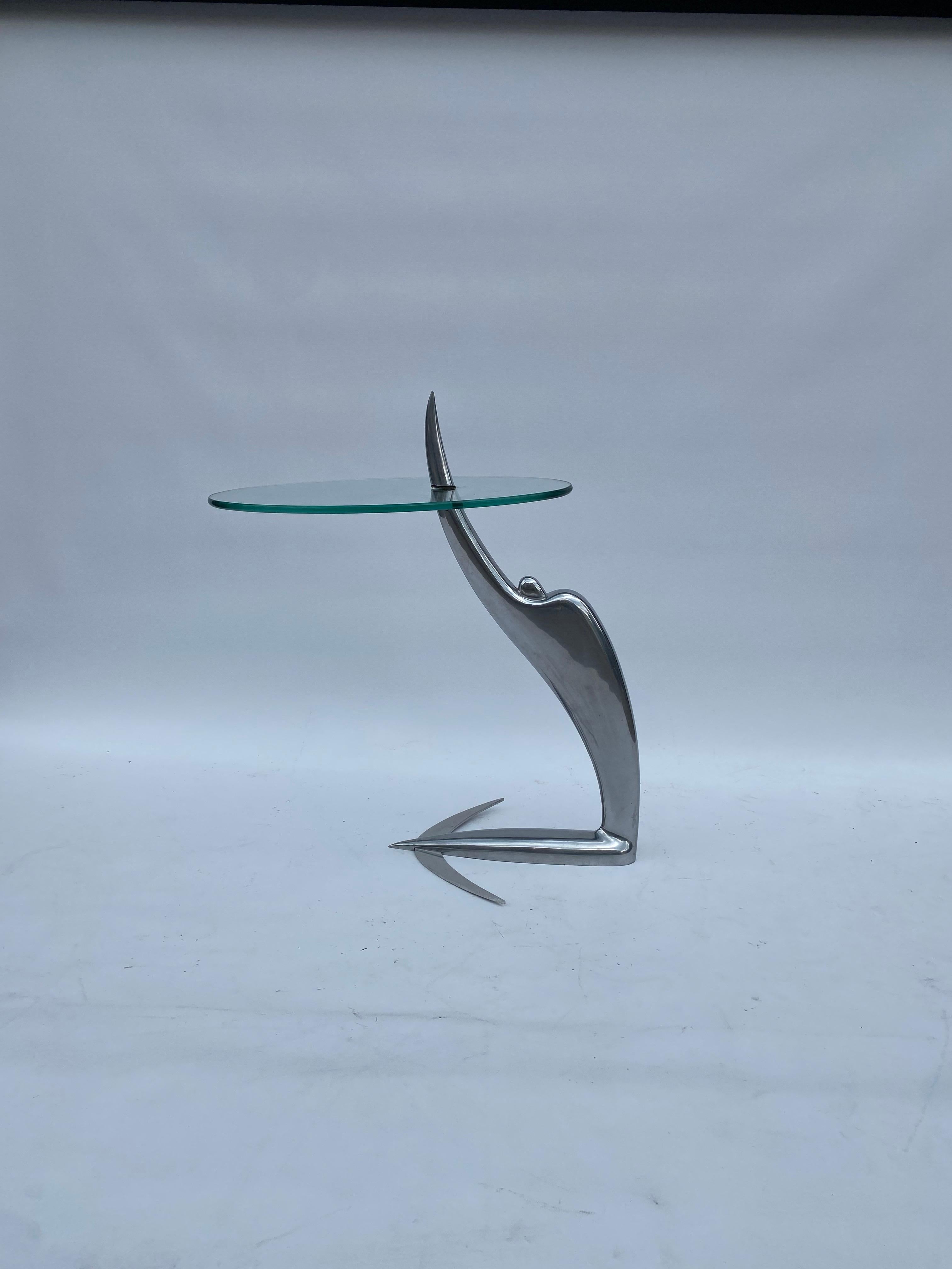 Signed Arcada Swing table by Pierangelo Caramia for the Phillipe Starke Label XO-Design, 1987

This an amazing petite side table featuring a futuristic aerodynamic figure in postmodernist manner holding the oval glass top. Inspired by Greek