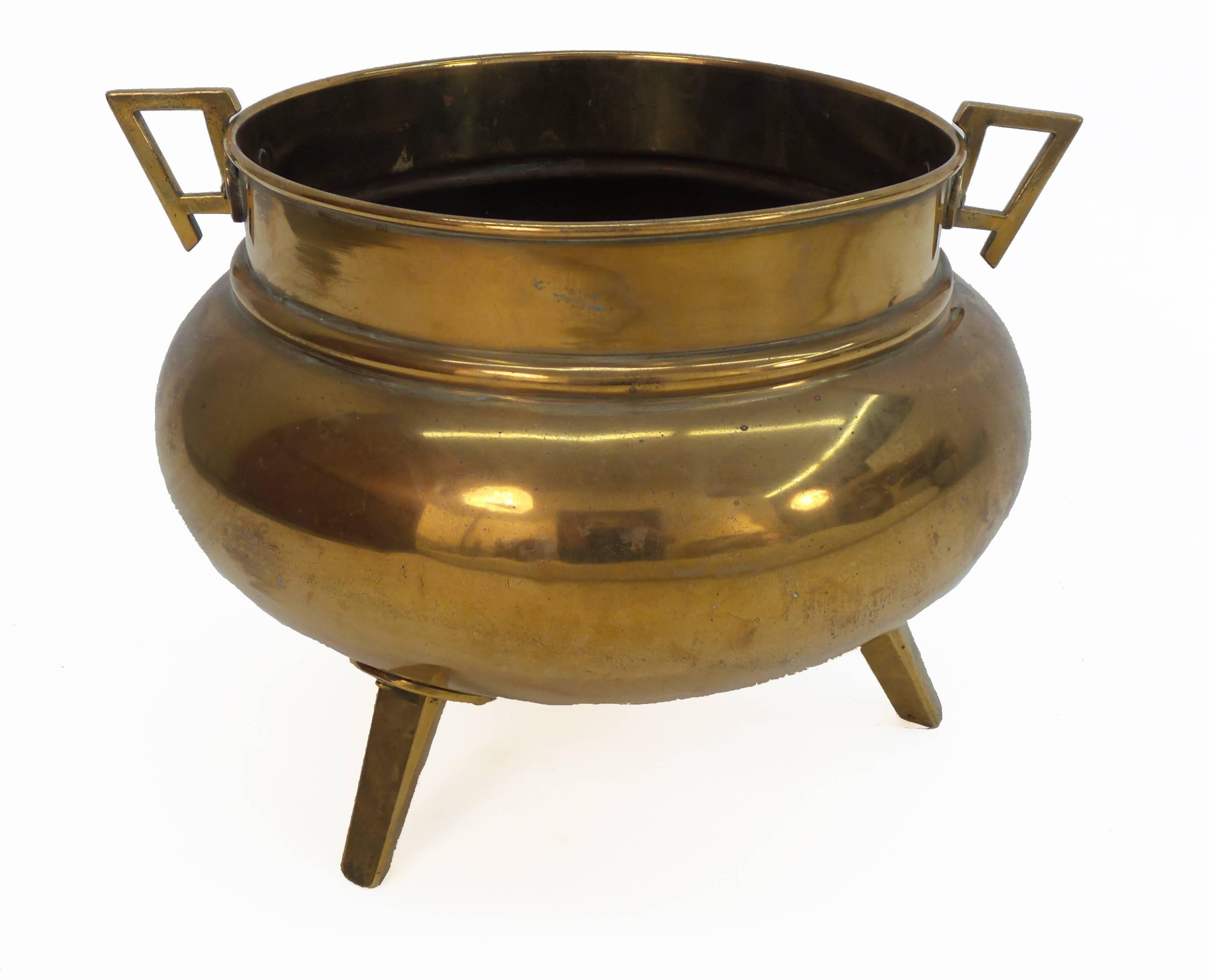 An English aesthetic movement brass tripodal coal skuttle, now planter, with removable handle. The design attributed to Christopher Dresser, circa 1890.