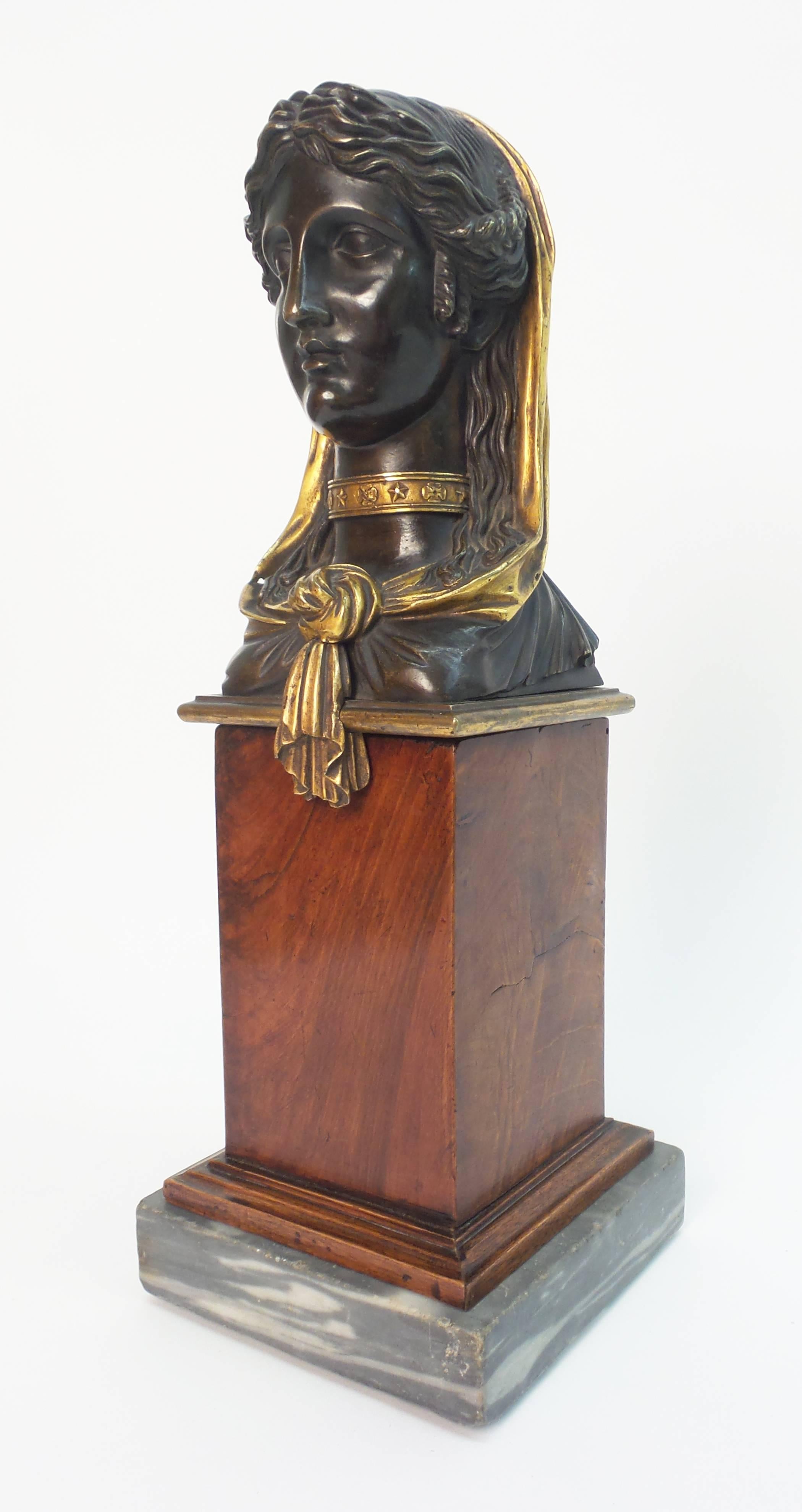 A fine Empire period gilt and patinated bronze sculpture of a female head dressed a l'antique mounted on a satin wood and bleu turquin marble base, the base of the same period and designed for this casting.